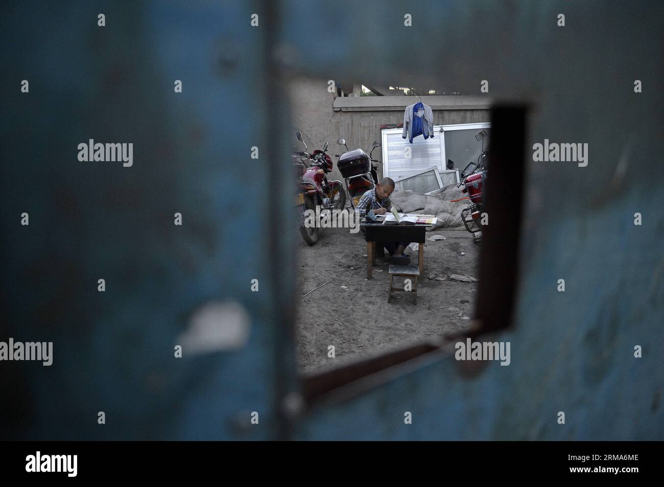 (140620) -- YINCHUAN, 20 giugno 2014 (Xinhua) -- Un ragazzo fa i compiti nel cortile di una villa nel nuovo villaggio di Wulitai a Yinchuan, regione autonoma Ningxia Hui della Cina nord-occidentale, 10 giugno 2014. Ci sono oltre 30 ville nel nuovo villaggio di Wulitai con un terzo incompleto a causa del default dei pagamenti per la costruzione. Quelle ville ora sono affittate ai lavoratori migranti. Una villa di 200 metri quadrati è stata separata in diverse stanze, e l'affitto di ognuna è di circa 300 yuan (circa 48,18 dollari USA). Per i lavoratori migranti che non hanno accesso a bungalow economici o non possono permettersi appartamenti, questa camera è un buon hotel Foto Stock