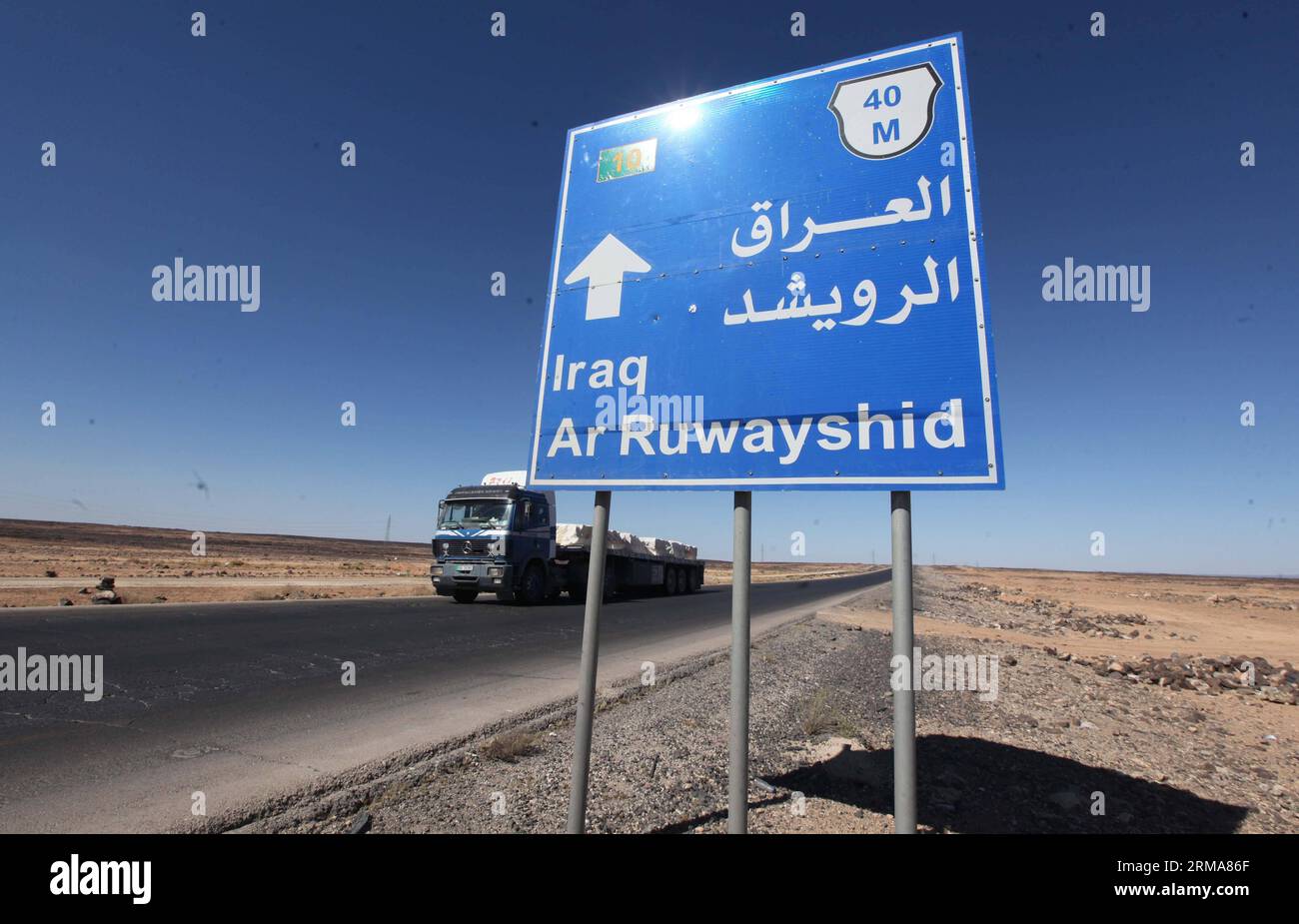 (140624) -- ATTRAVERSAMENTO DI AL KARAMAH, 24 giugno 2014 (Xinhua) -- Un camion giordano è visto vicino a un cartello che mostra la distanza da AR Ruwayshid, vicino al confine iracheno, il 23 giugno 2014. Lunedì la Giordania ha iniziato a mobilitare le forze lungo il confine con l'Iraq per evitare infiltrazioni di militanti sunniti in un peggioramento della situazione della sicurezza in Iraq. (Xinhua/Mohammad Abu Ghosh) (zjl) JORDAN-AL KARAMAH CROSSING-IRAQ-PREVENTION PUBLICATIONxNOTxINxCHN al Crossing 24 giugno 2014 XINHUA un camion giordano È Lakes Near a Sign Thatcher mostra la distanza dall'AR vicino al confine iracheno IL 2 giugno Foto Stock