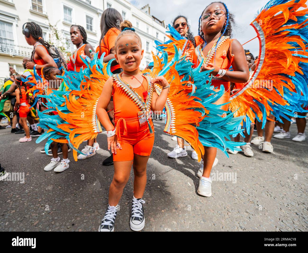 Londra, Regno Unito. 27 agosto 2023. I bambini in costume piumato seguono il camion della musica del secondo gruppo della sfilata ufficiale - la domenica del Carnevale di Notting Hill, tradizionalmente giorno dei bambini. L'evento annuale per le strade del Royal Borough di Kensington e Chelsea, durante il fine settimana festivo di agosto. È guidato da membri della comunità britannica delle Indie occidentali e attrae circa un milione di persone all'anno, rendendolo uno dei più grandi festival di strada del mondo. Crediti: Guy Bell/Alamy Live News Foto Stock