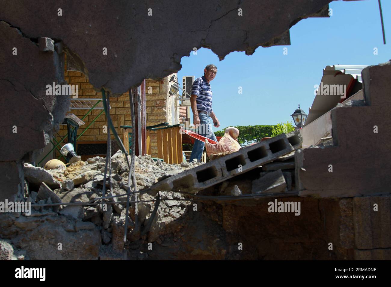 (140703) -- SDEROT (ISRAELE), 3 luglio 2014 (Xinhua) -- un uomo israeliano ispeziona i danni di una casa a seguito di un attacco proiettile da parte di militanti da Gaza a Sderot, Israele, il 3 luglio 2014. All'inizio di giovedì, tre proiettili hanno colpito edifici residenziali nella città israeliana di Sderot, tra cui un appartamento che funge da asilo privato. I razzi spararono durante la notte e distrussero l'elettricità in alcune parti della città. La maggior parte degli altri proiettili sparati giovedì hanno colpito aree aperte, senza causare lesioni. Due razzi sono stati intercettati dal sistema di difesa israeliano Iron Dome e alcuni sono caduti corti e la Foto Stock