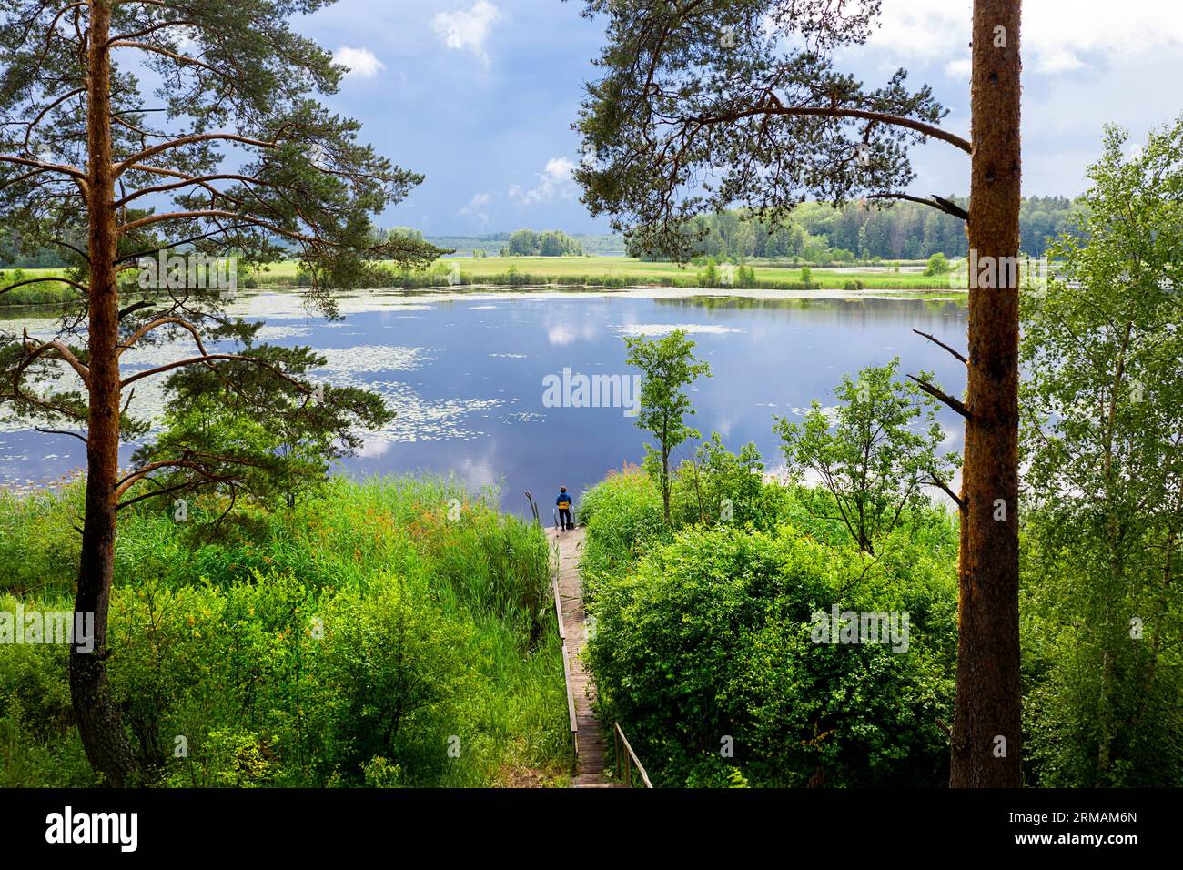 Pesca turistica ragazzo dopo la tempesta estiva alla fine di un molo di legno sul lago Joemoisa vicino al lago Peipus, Mustavee, Estonia Foto Stock