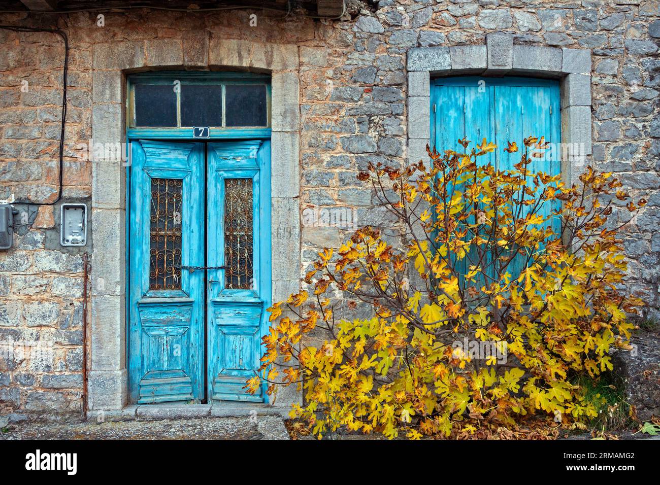 Vecchia casa in pietra abbandonata con porta doppia e finestra dai colori luminosi, nel pittoresco villaggio di Levidi, regione dell'Arcadia, Peloponneso, Grecia. Foto Stock