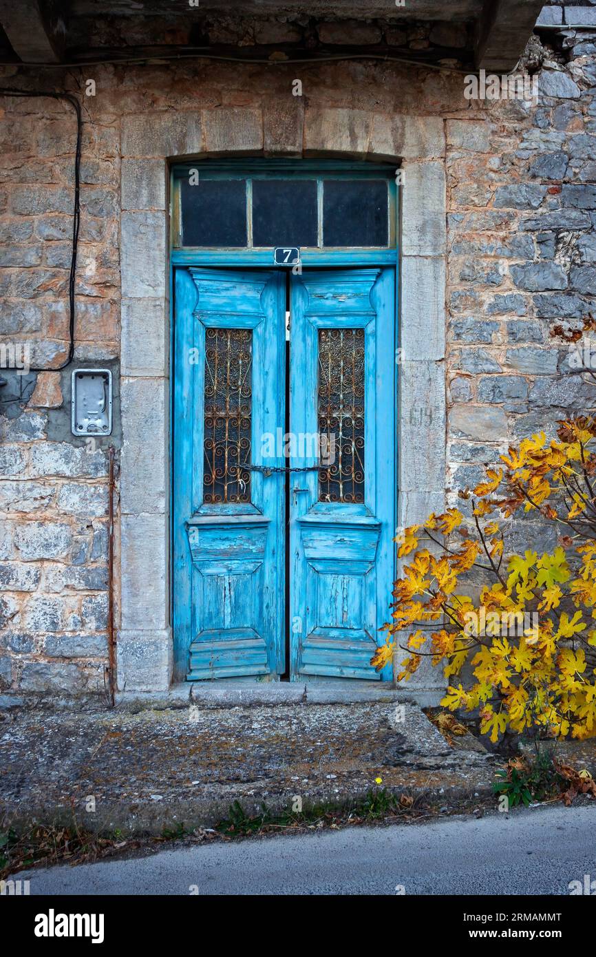 Vecchia casa in pietra abbandonata con porta doppia e finestra dai colori luminosi, nel pittoresco villaggio di Levidi, regione dell'Arcadia, Peloponneso, Grecia. Foto Stock