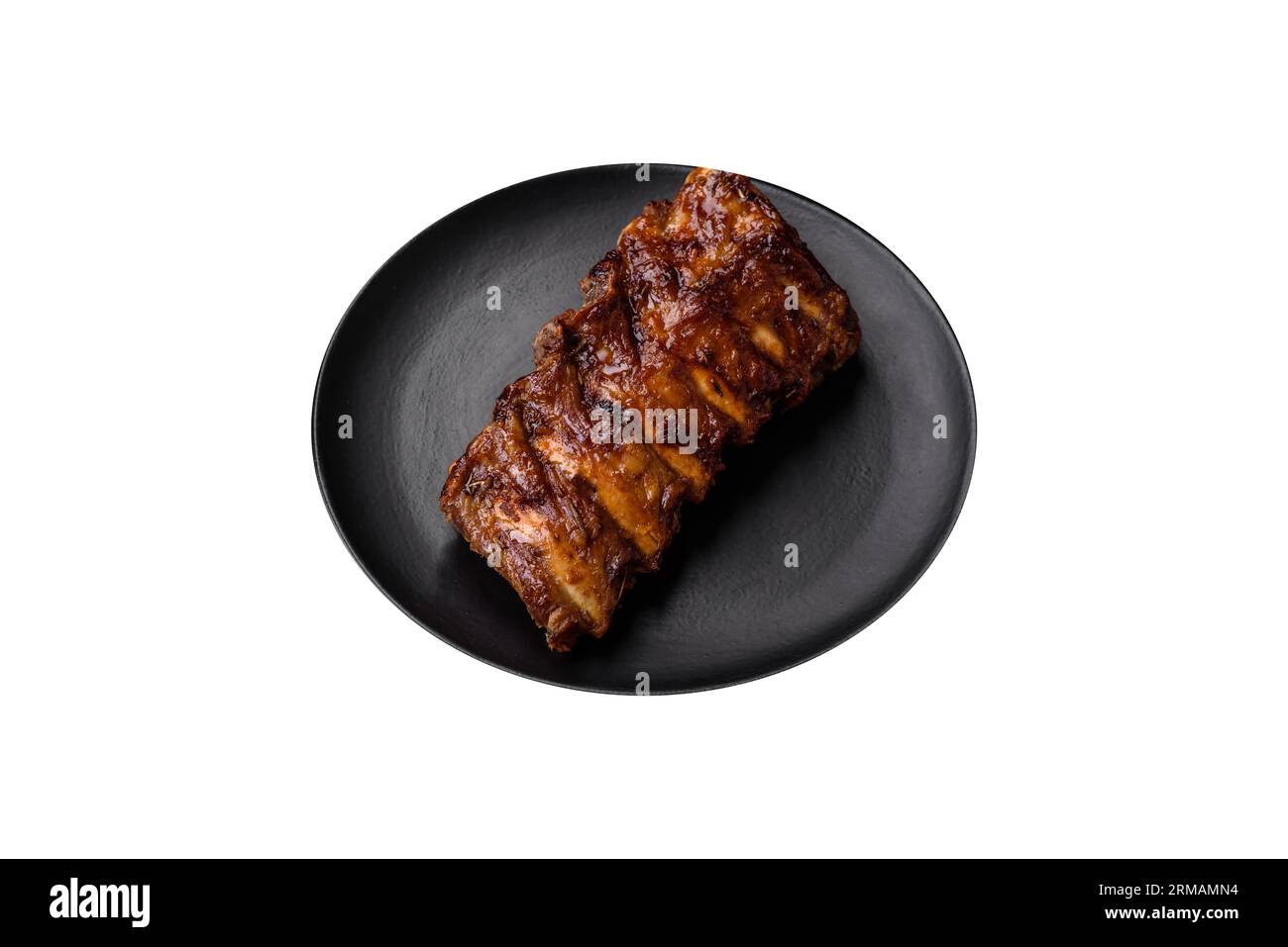 Deliziose costolette di maiale alla griglia con salsa, spezie ed erbe su fondo di cemento scuro Foto Stock