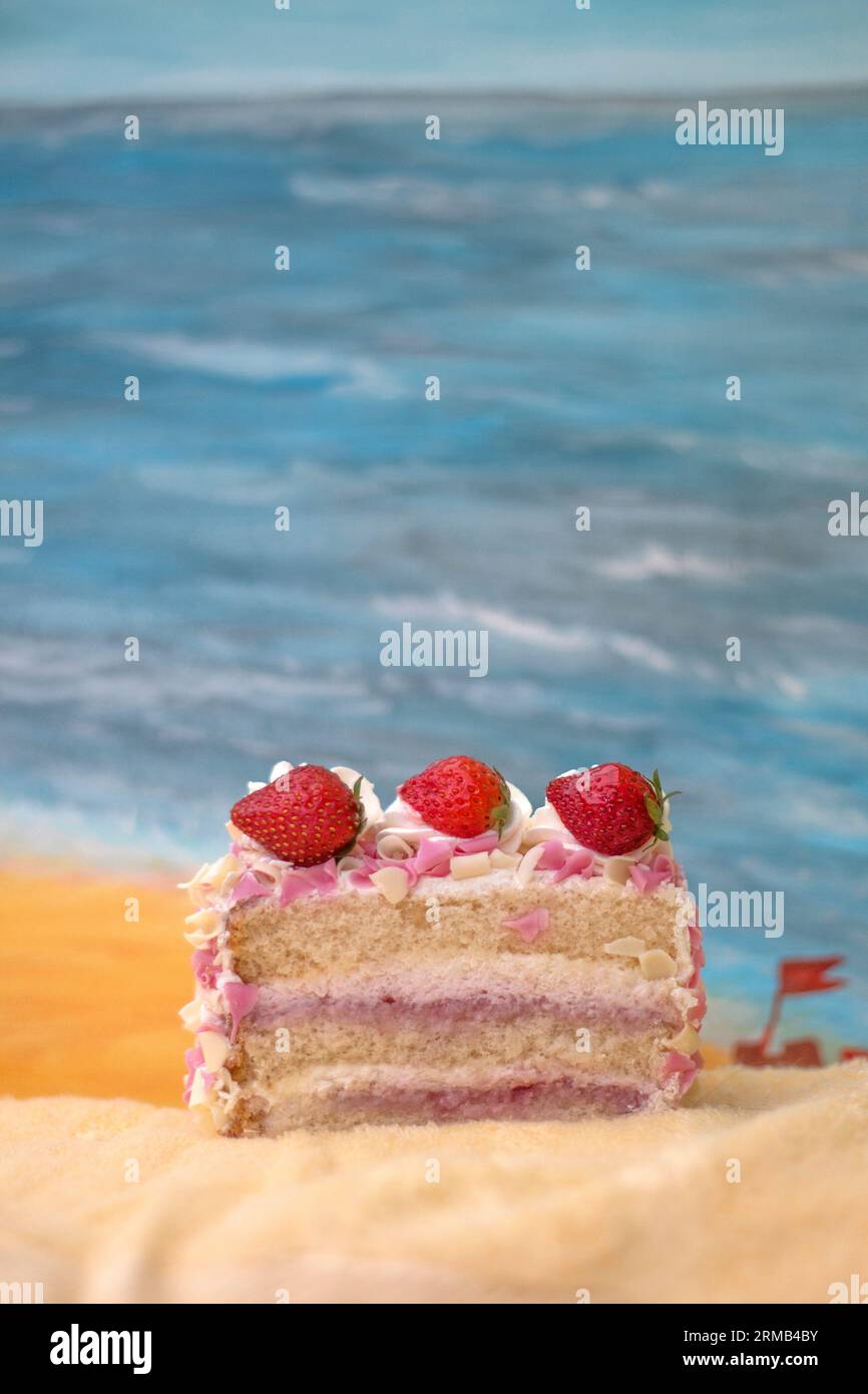 Scena della spiaggia con fragole rosa e torta alla crema per feste per occasioni speciali o compleanni Foto Stock