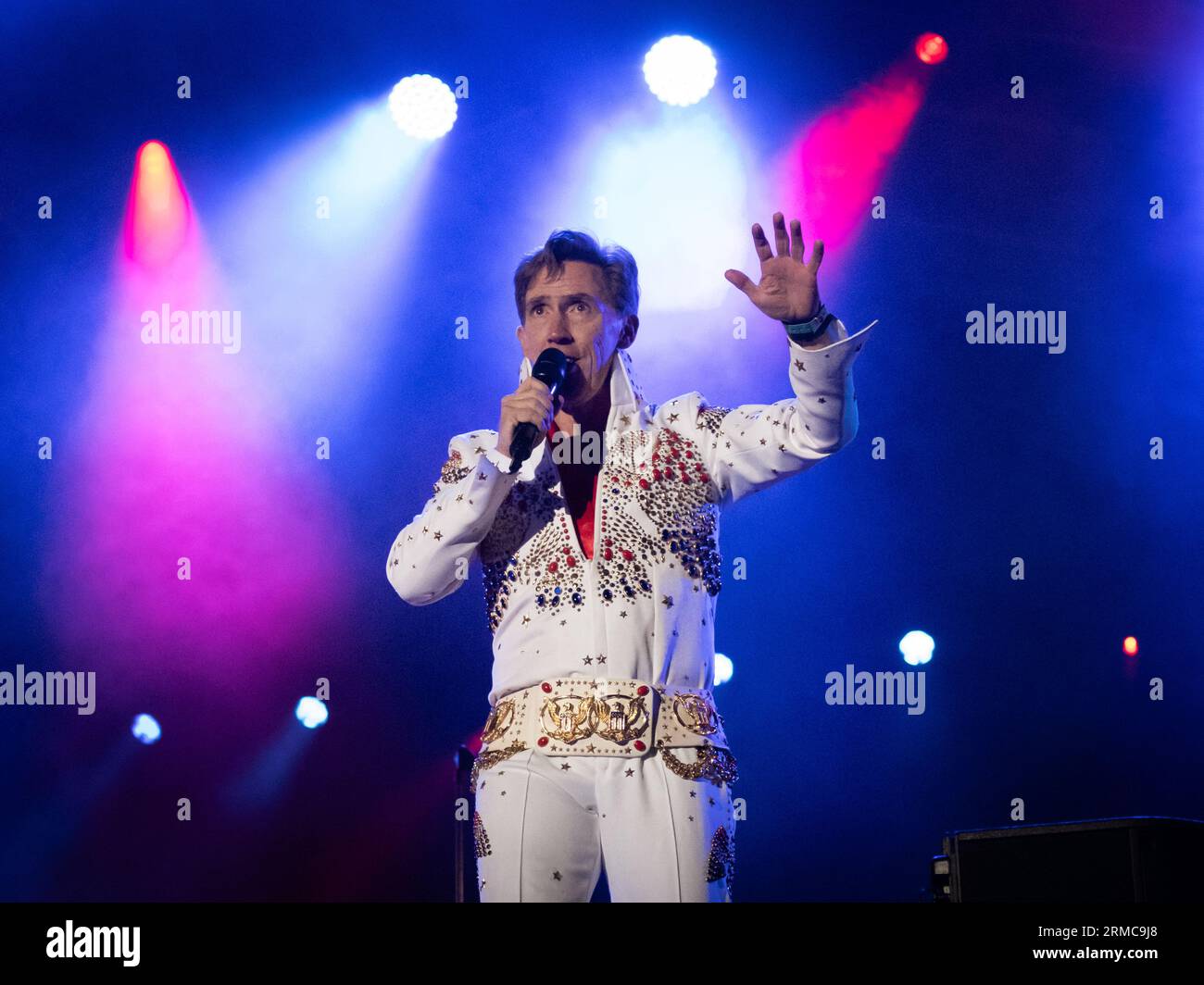 Rob Brydon sul palco principale del Carfest 2023, esibendosi come Terry Jenkins, un imitatore di Elvis con il Supergruppo. Foto Stock