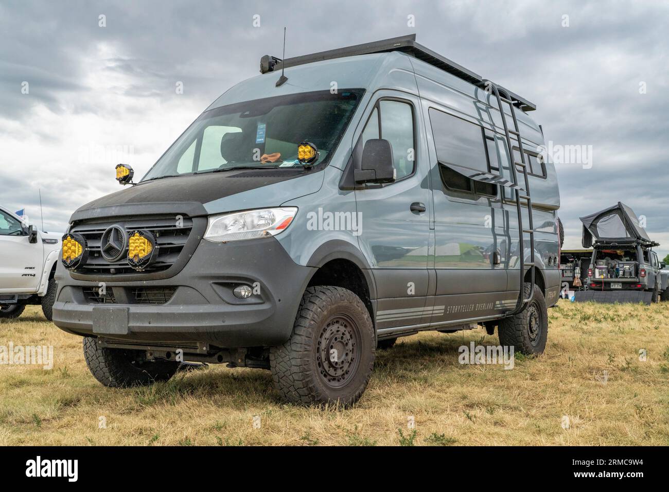Loveland, CO, USA - 25 agosto 2023: Storyteller Overland Stealth Mode, furgone camper 4x4 su telaio Mercedes Sprinter in un campeggio affollato. Foto Stock