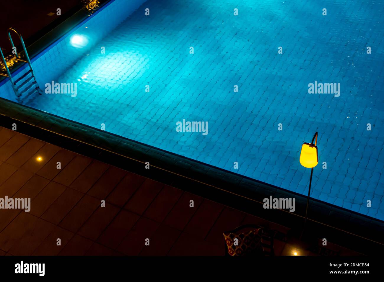 Palo giallo sopra l'acqua blu della piscina, scatto notturno. Foto Stock