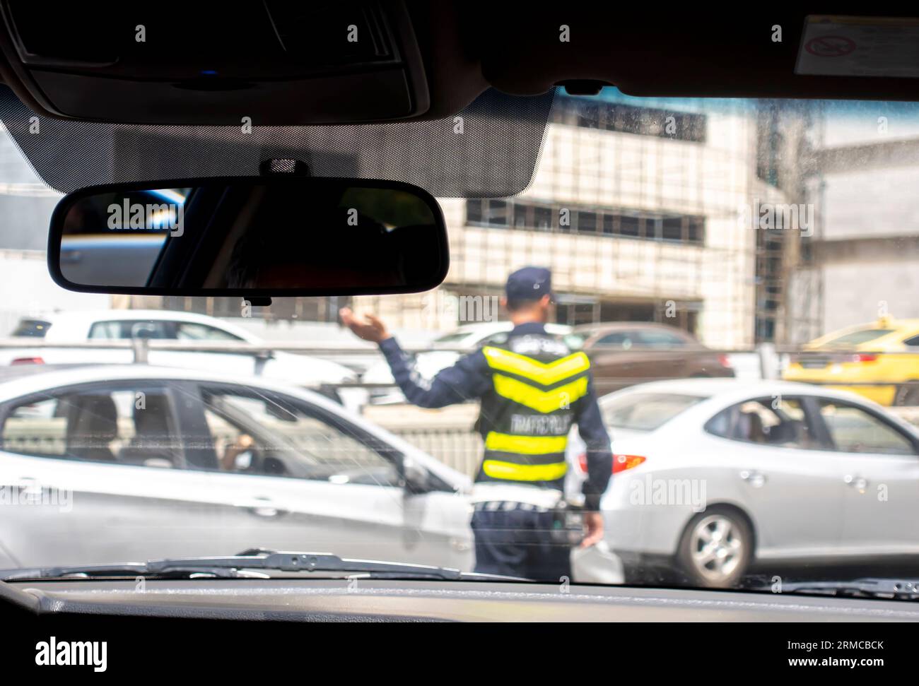 Agente di polizia stradale in mezzo alla strada che regola il traffico nella trafficata strada di Amman in Giordania. Immagine sfocata di un poliziotto del traffico Foto Stock Agente di polizia stradale in mezzo alla strada che regola il traffico nella trafficata strada di Amman in Giordania. Immagine sfocata di un poliziotto del traffico Foto Stock
