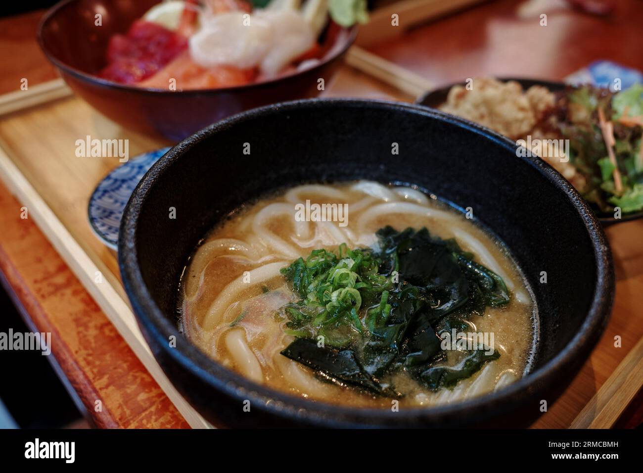 Messa a fuoco selettiva alla zuppa di spaghetti miso udon e sfocatura dello sfondo di Sashimi Don, Danburi o riso giapponese con varie ciotola cruda fresca. Foto Stock
