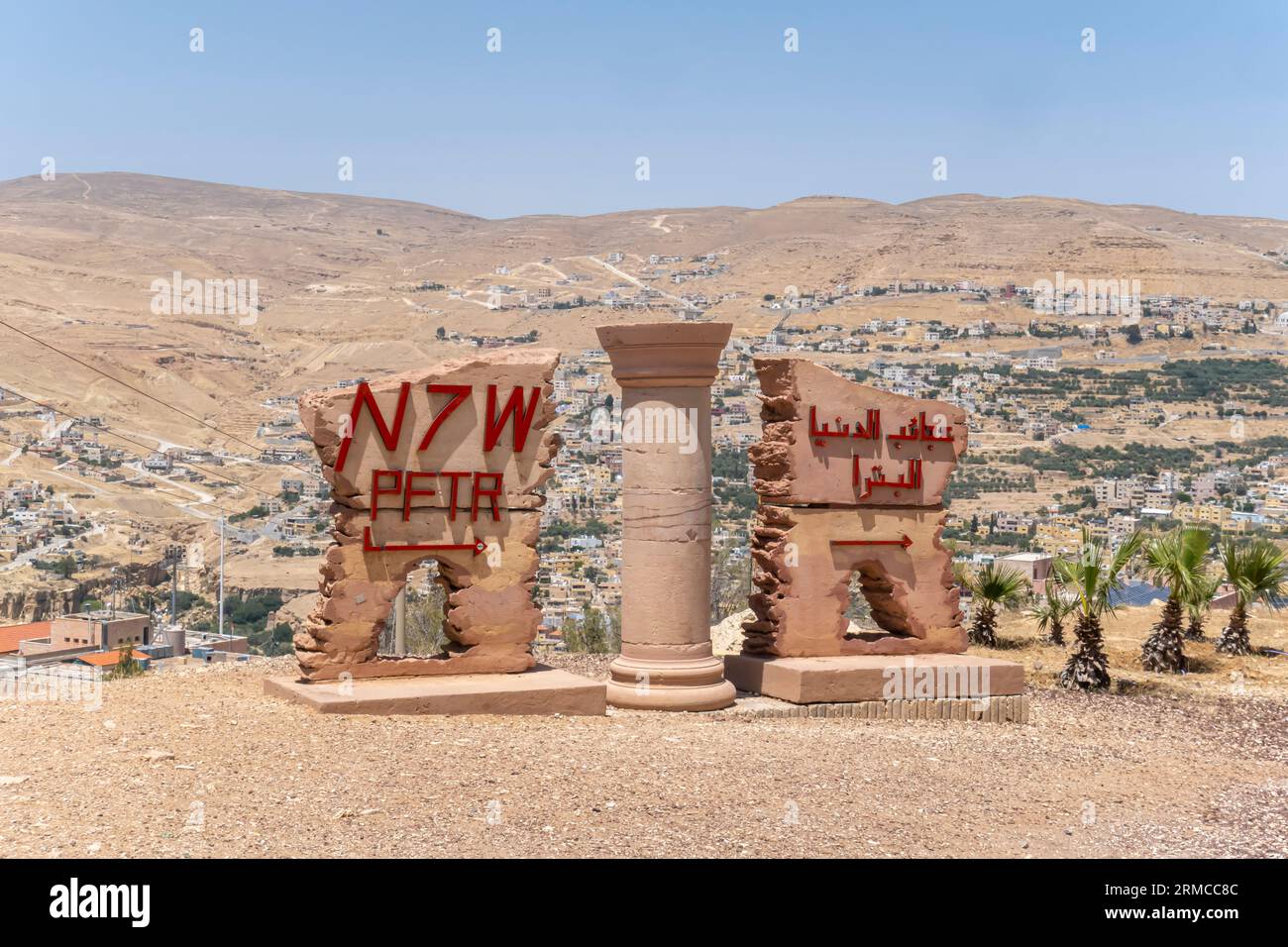 Monumento di Petra Jordan e segno distintivo della città, insegna bilingue a Petra Jordan. Punto panoramico sulle montagne di Petra che si affacciano sulla città di Wadi Musa Foto Stock