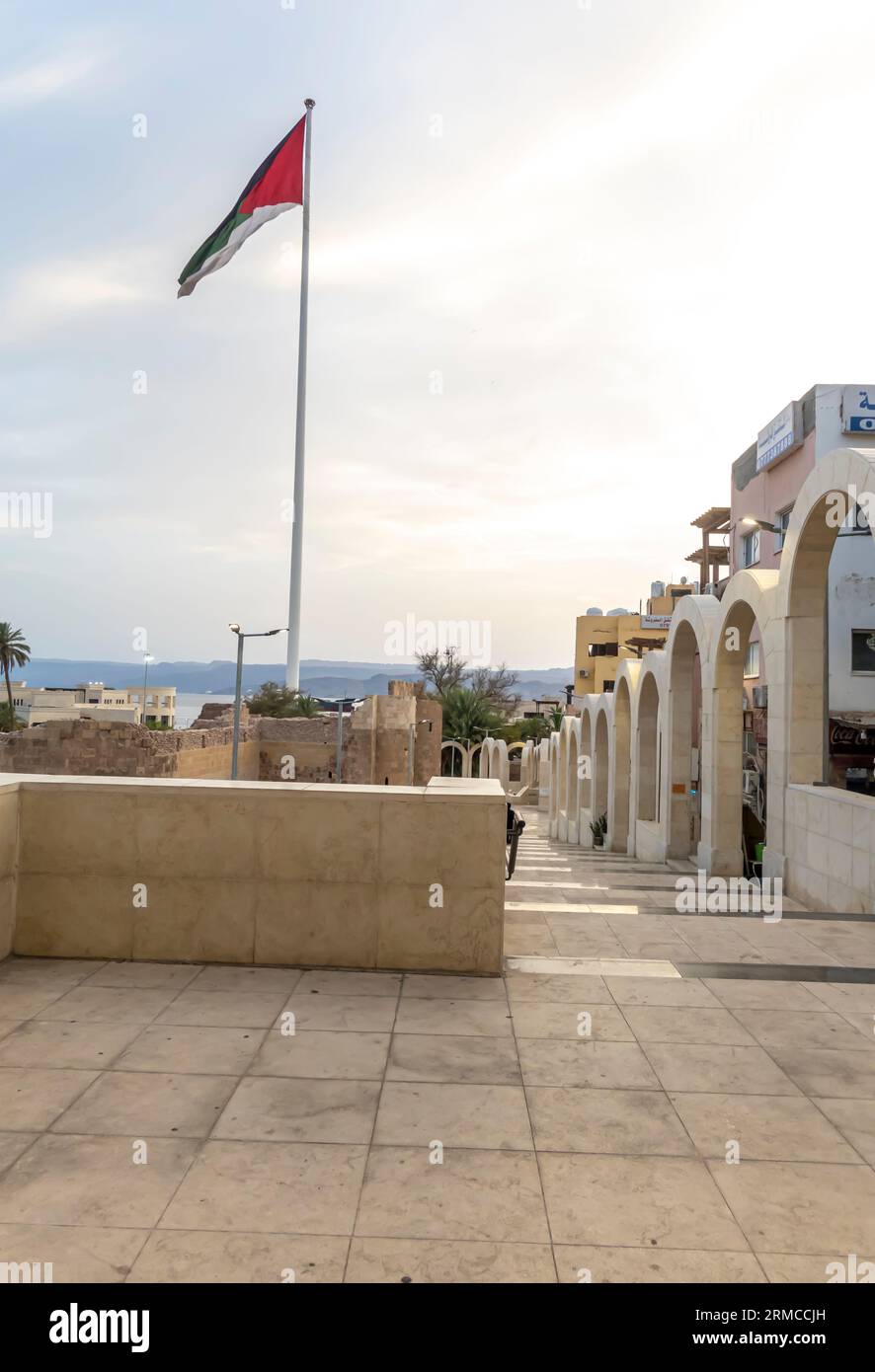 Bandiera della Giordania su un'asta di bandiera nella rivolta araba, vista attraverso le strette strade di Aqaba in Giordania Foto Stock
