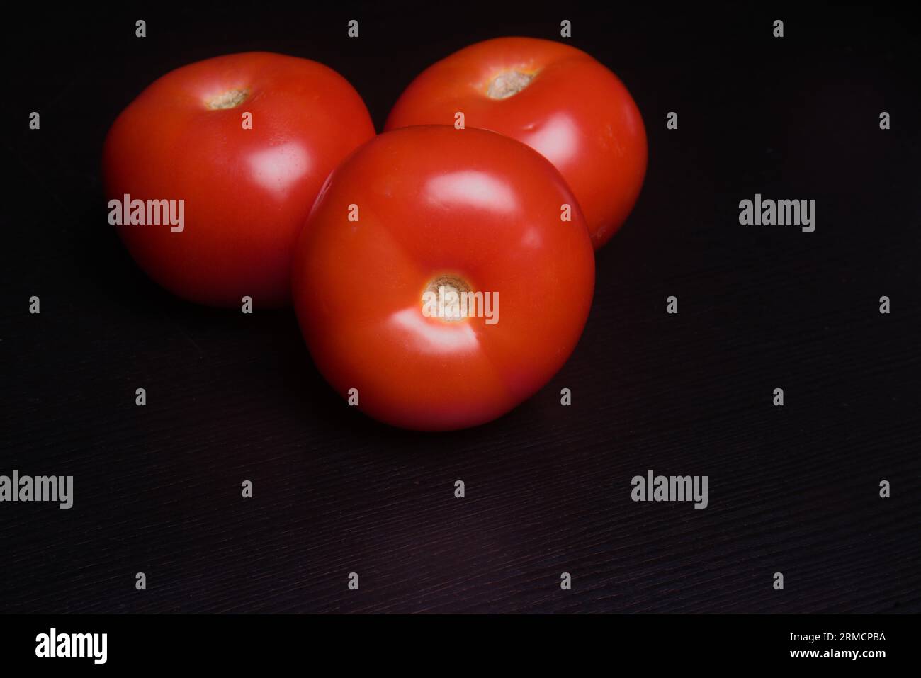 Primo piano di 3 pomodori maturi sul tavolo nero, Simle STILL Life di uno dei punti chiave della natura per vivere. Foto Stock