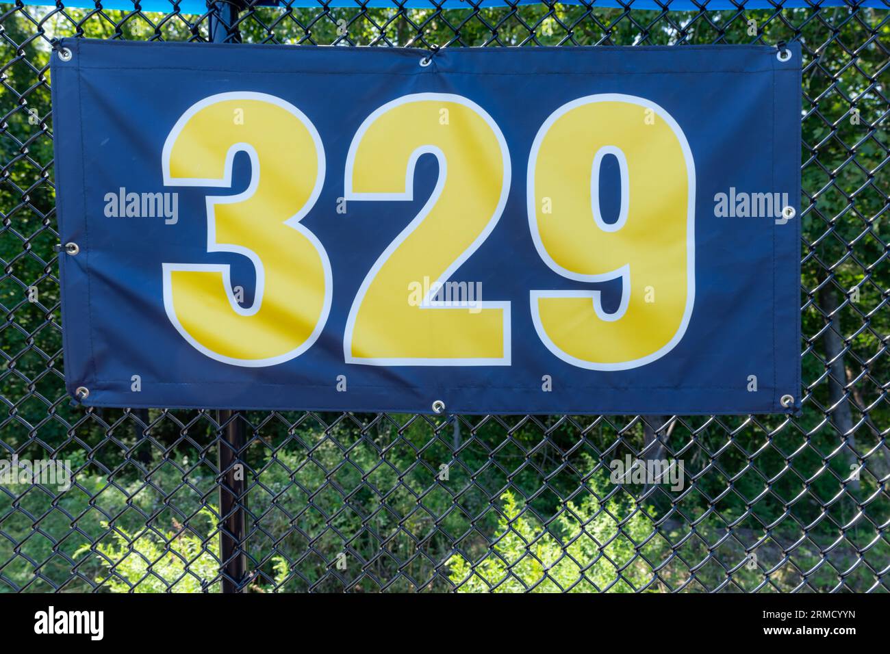 cartello distanza campo da baseball di 329 metri circa giallo e nero montato sulla recinzione esterna in vinile nero. Foto Stock