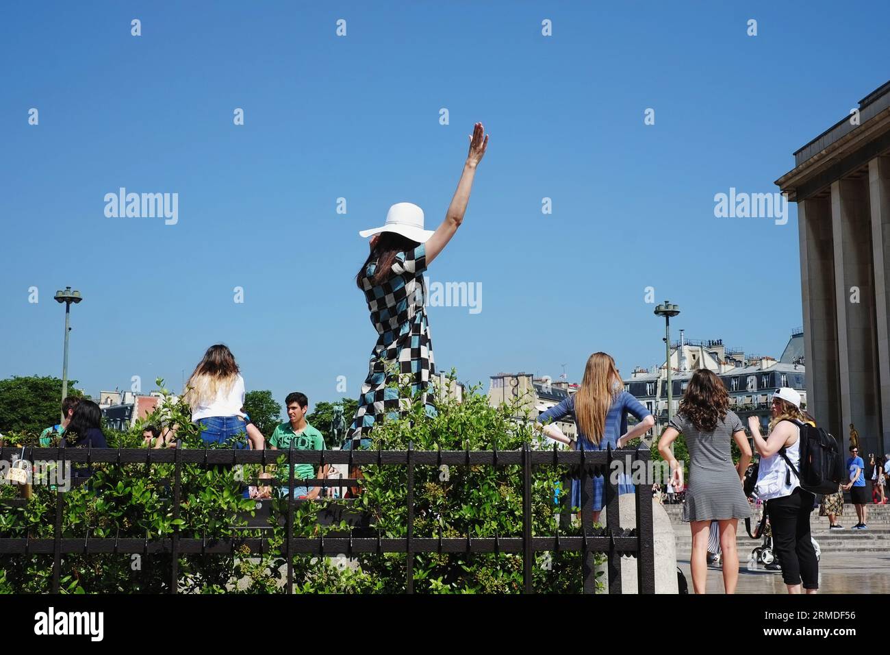 In Place du Trocadéro, una donna con abito a quadri e cappello bianco regge  un braccio, una posa da fotografare con la Torre Eiffel (invisibile Foto  stock - Alamy