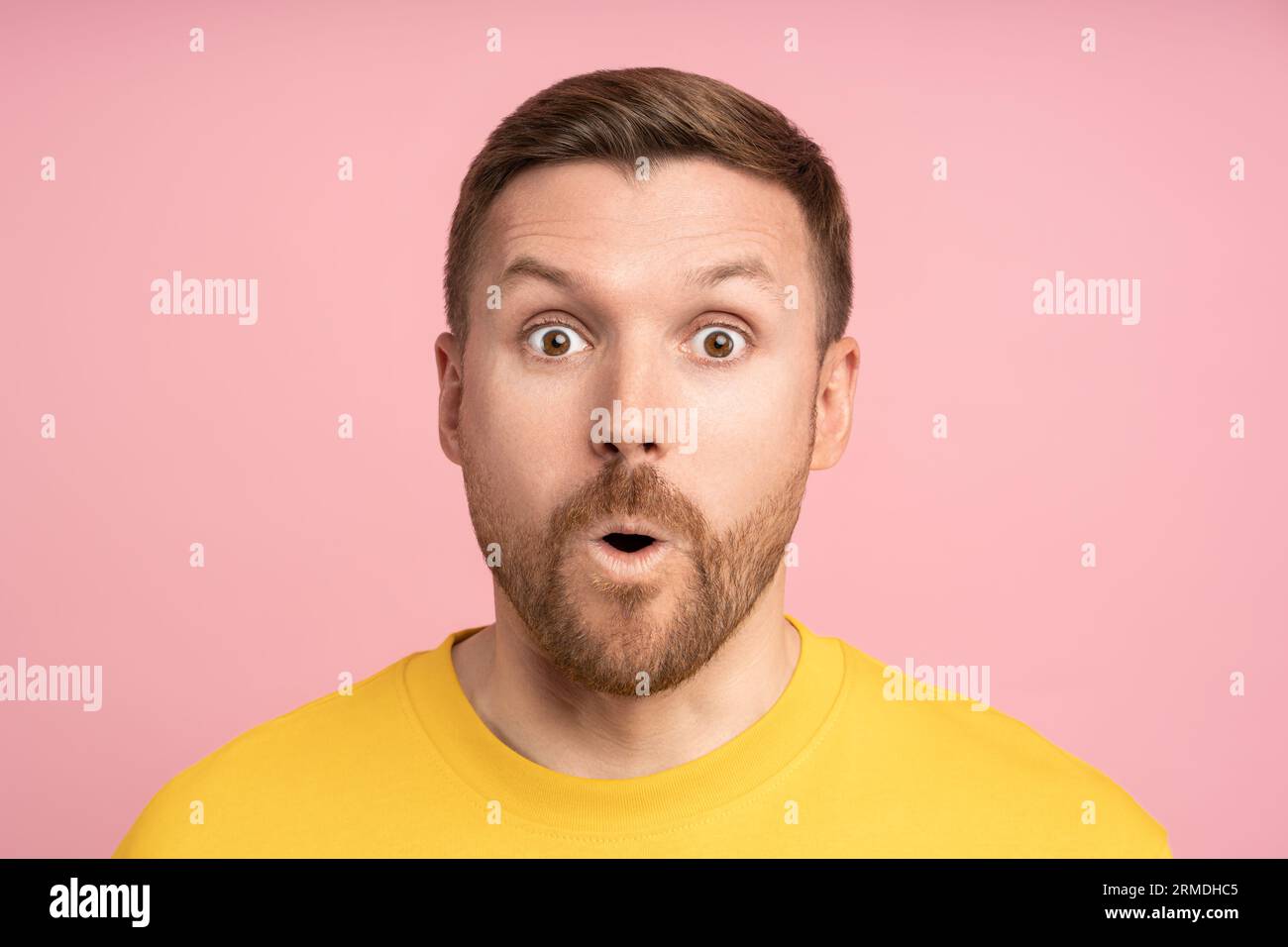 Un uomo stupito che guarda a bocca aperta sorprende l'espressione con gli occhi grandi e lo sfondo rosa isolato dello studio. Foto Stock