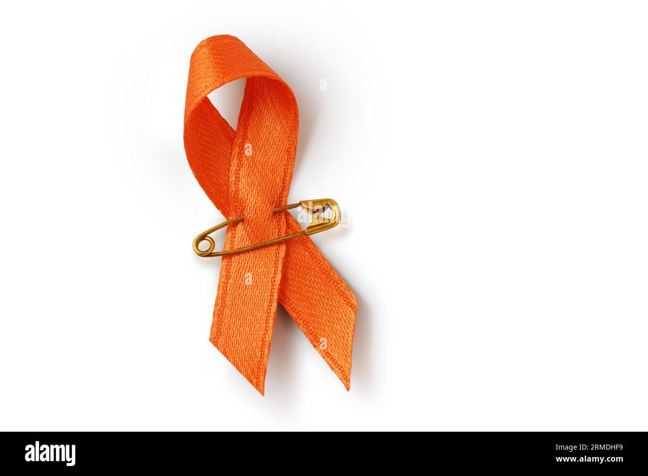 Nastro arancione con spilla di sicurezza su sfondo bianco - concetto di sensibilizzazione alla leucemia, associazione del cancro ai reni, sclerosi multipla e abuso di animali Foto Stock