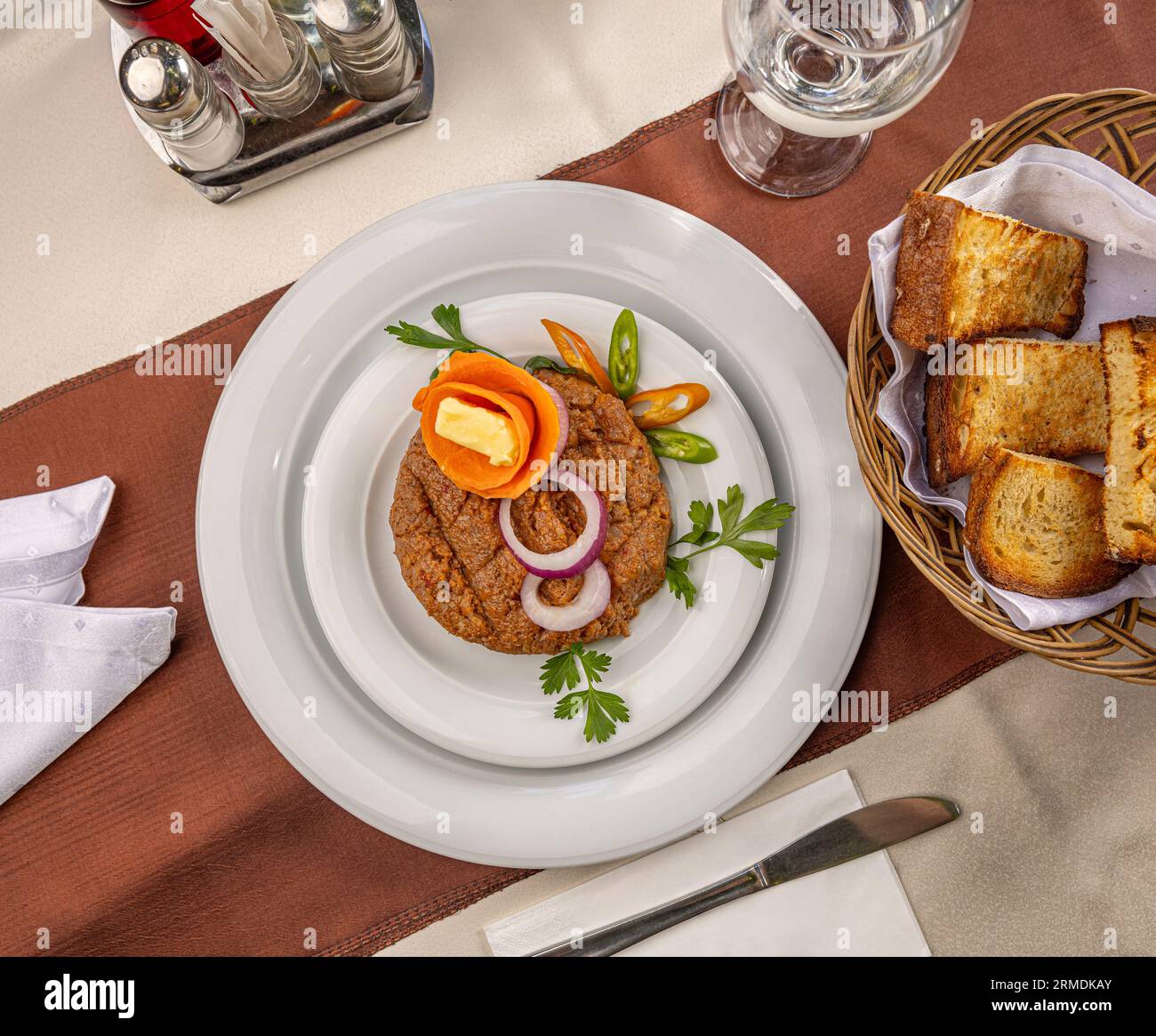 Piatto di tartare di manzo con anelli di cipolla servito con pane tostato Foto Stock