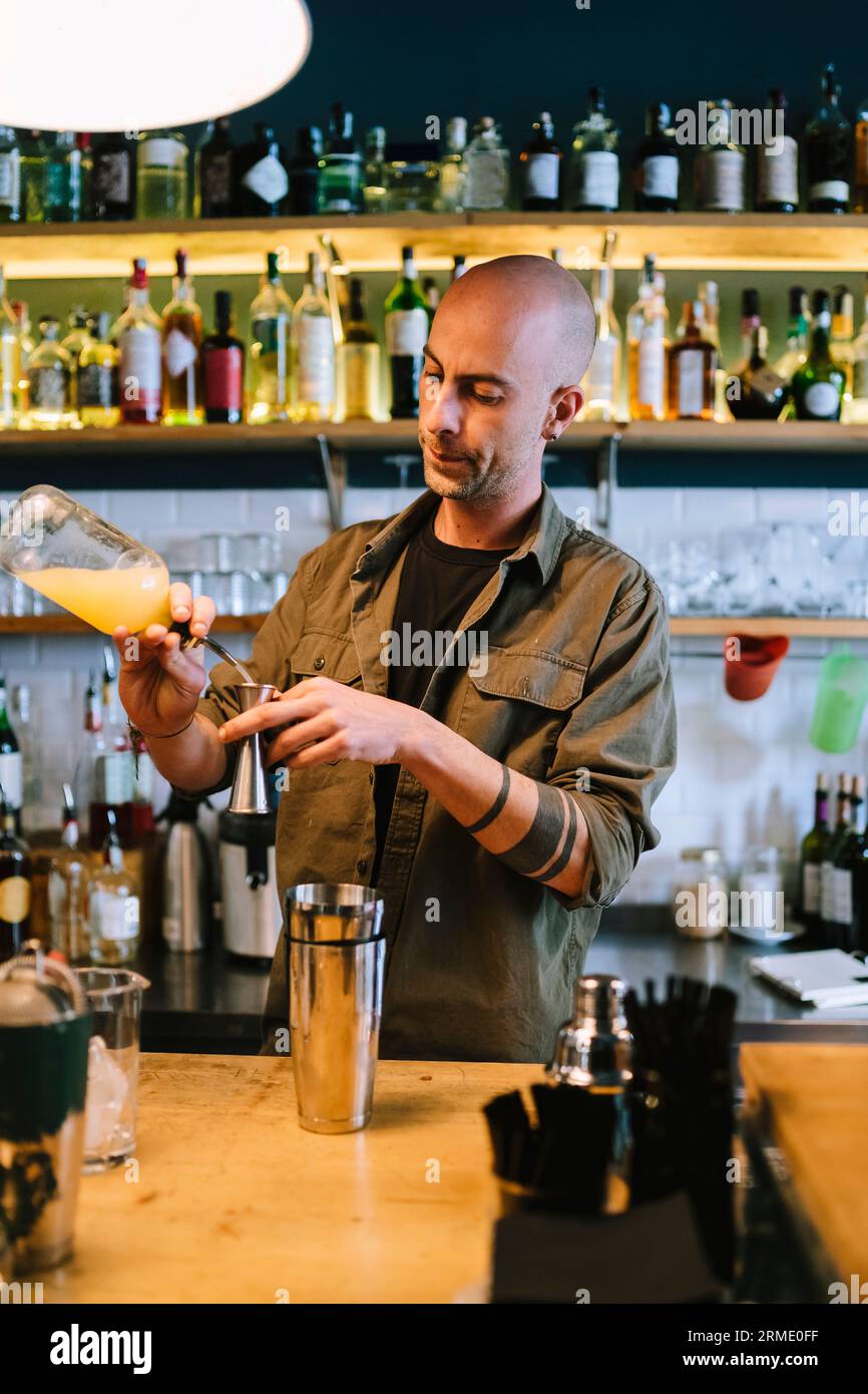 Il giovane barman prepara un cocktail alcolico al bar Foto Stock