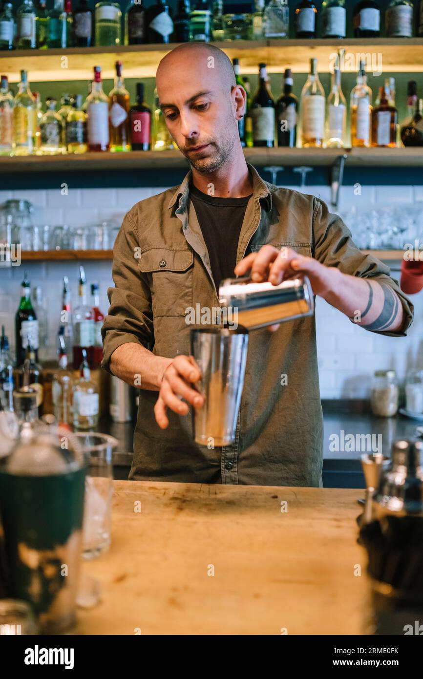 Il giovane barman prepara un cocktail alcolico al bar Foto Stock
