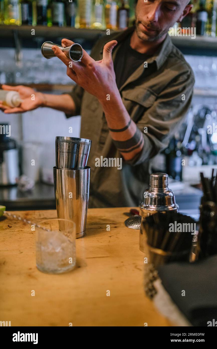 Il giovane barman prepara un cocktail alcolico al bar Foto Stock