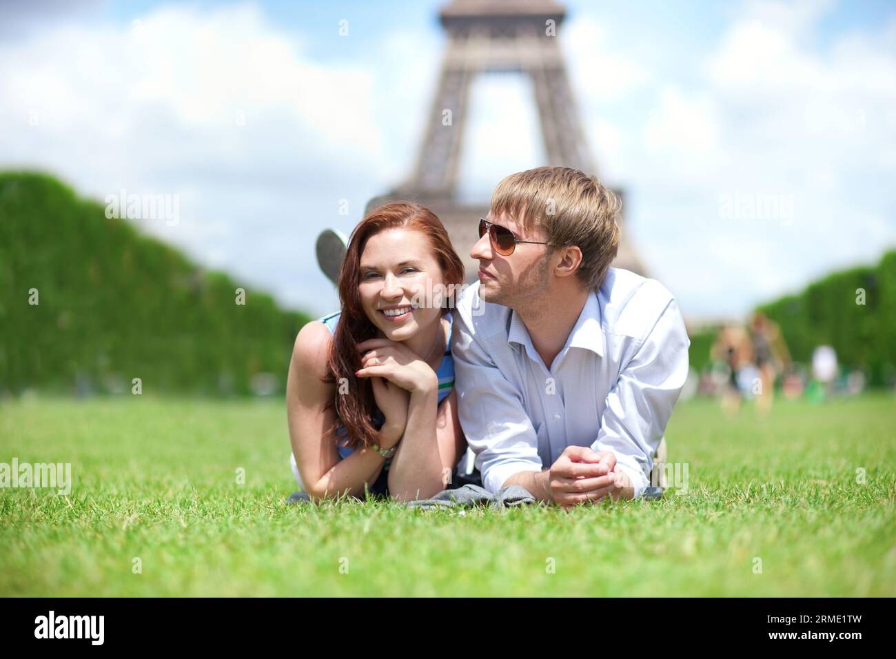 Primo piano di una felice coppia positiva stesa sull'erba a Parigi Foto Stock