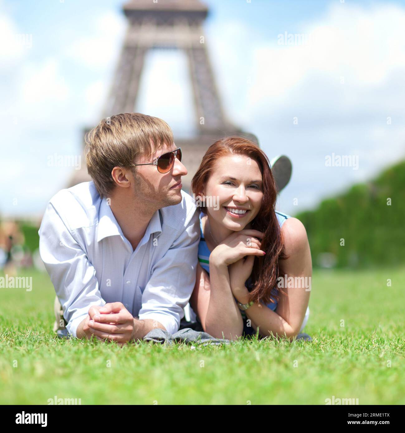 Primo piano di una felice coppia positiva stesa sull'erba a Parigi Foto Stock