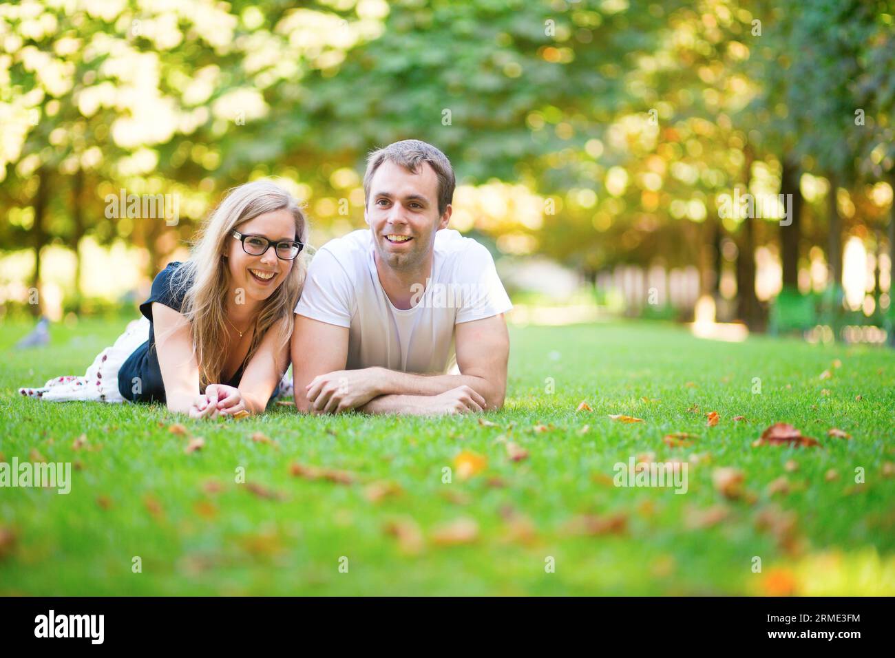 Felice coppia sorridente sdraiata sull'erba Foto Stock