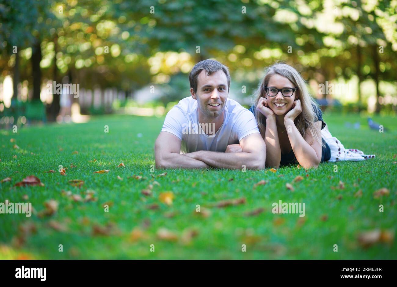 Felice coppia sorridente sdraiata sull'erba Foto Stock
