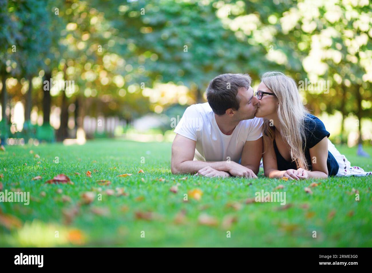 Coppia sdraiata sull'erba e baciata Foto Stock