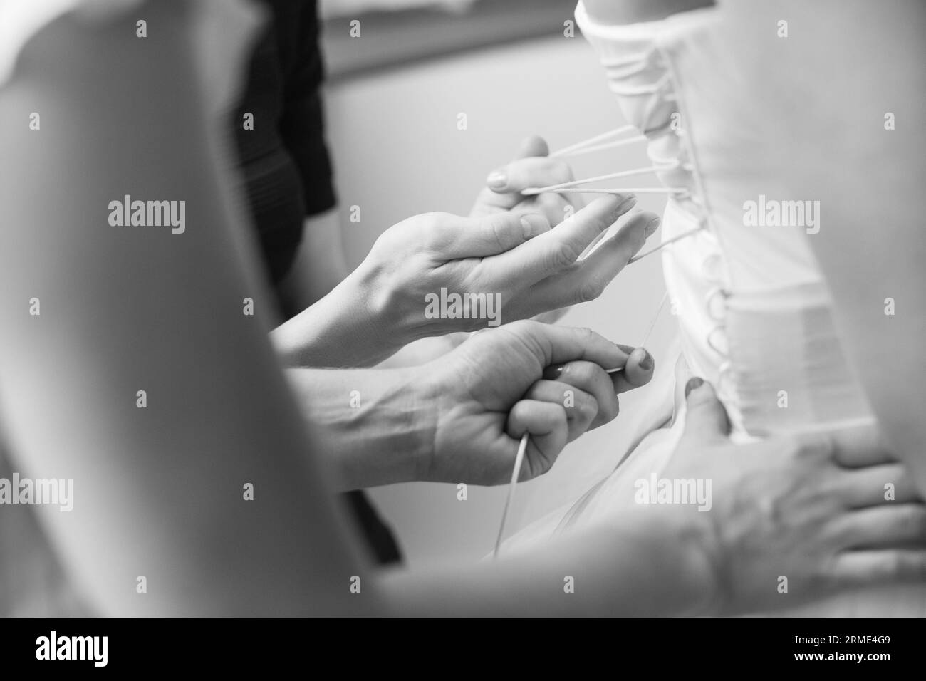 Damigelle che aiutano la sposa a indossare il suo vestito da sposa Foto Stock