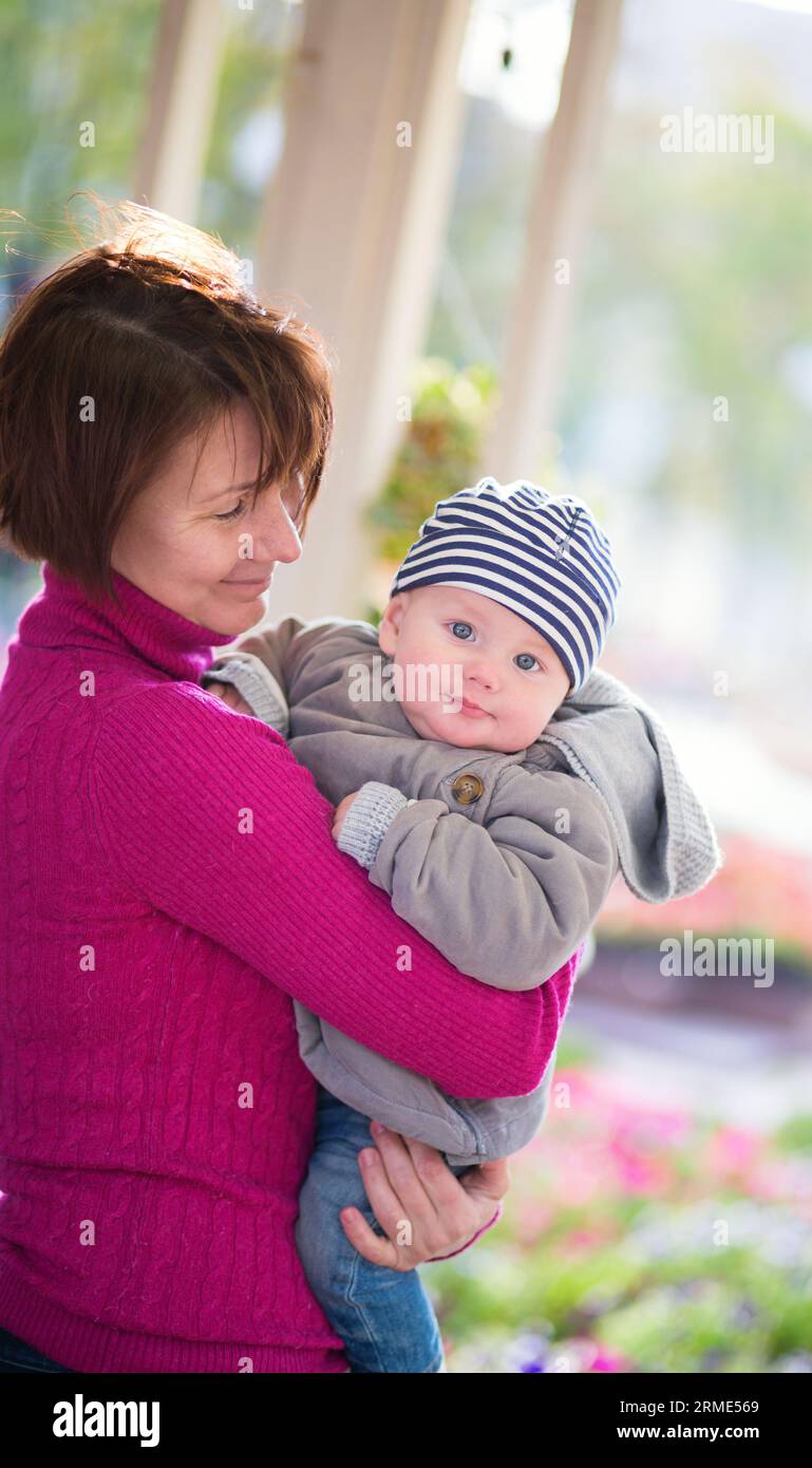 La bella donna di mezza età e il suo adorabile nipotino si divertono insieme in un caffè all'aperto in autunno o primavera Foto Stock