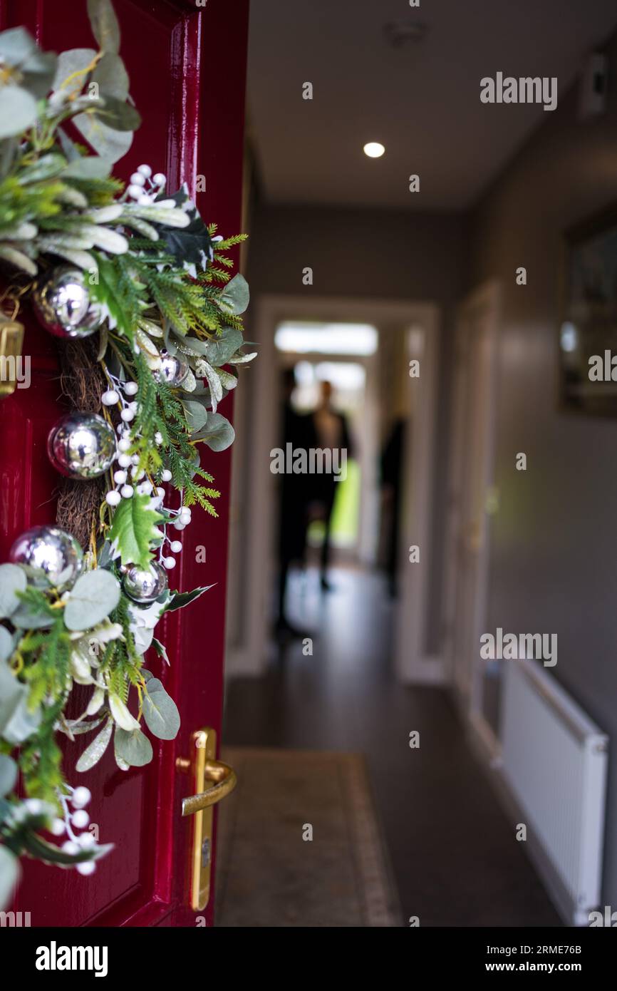 la corona di natale adorna la porta rossa con fascino festivo Foto Stock