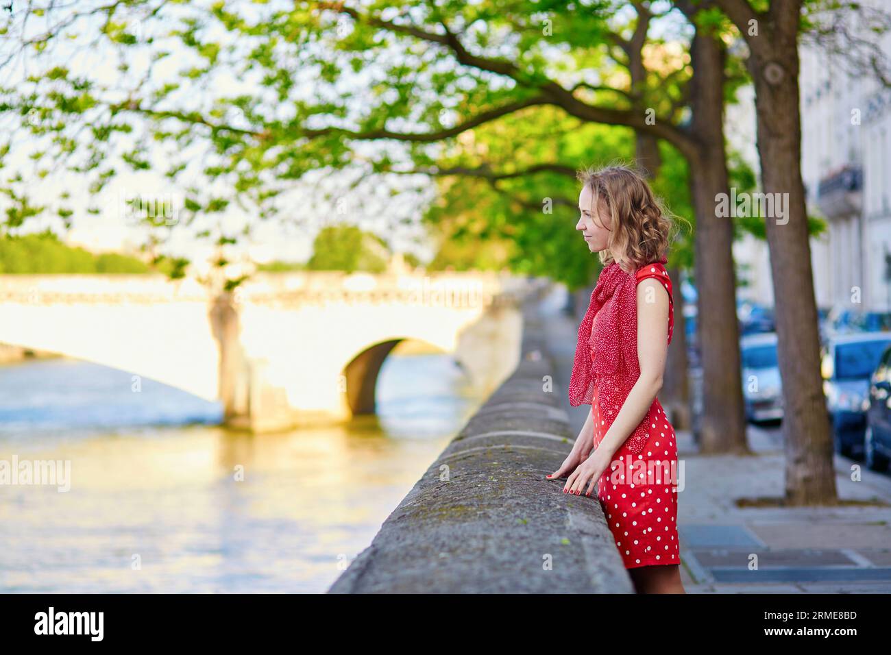 Bella giovane donna con abito rosso a pois vicino alla Senna in una bella giornata estiva Foto Stock