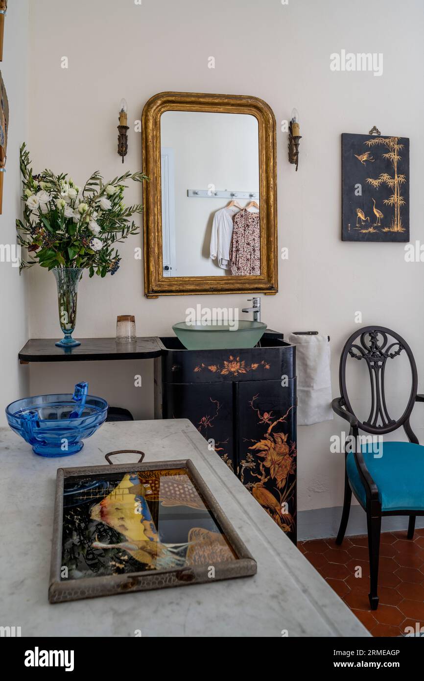 Specchio con cornice dorata sopra il lavandino dipinto a mano con vassoio laccato cinese nella camera da letto Cotignac, Var, Francia. Foto Stock