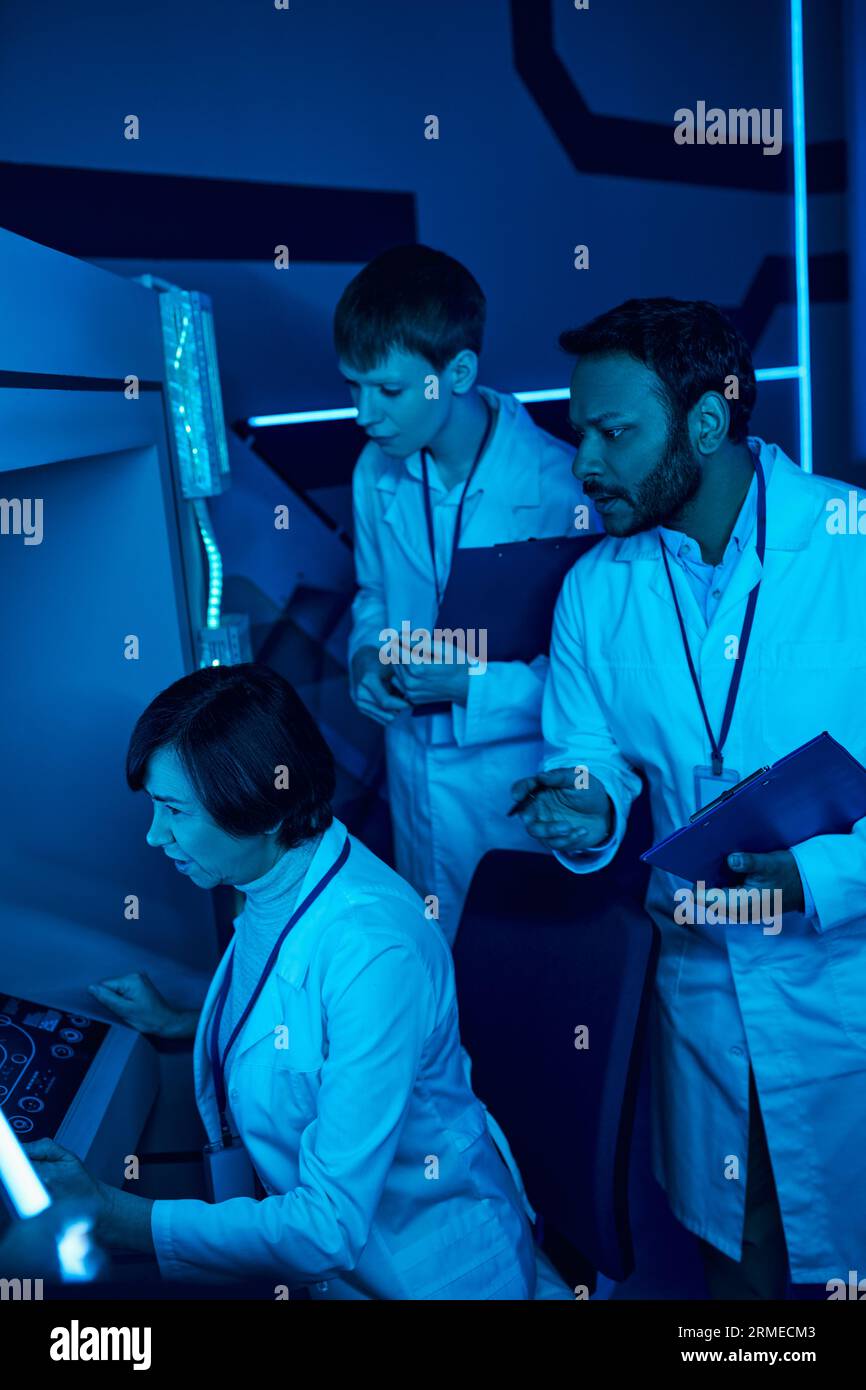 Exploring Tomorrow: Tre scienziati collaborano vicino al computer futuristico nel Science Center Foto Stock