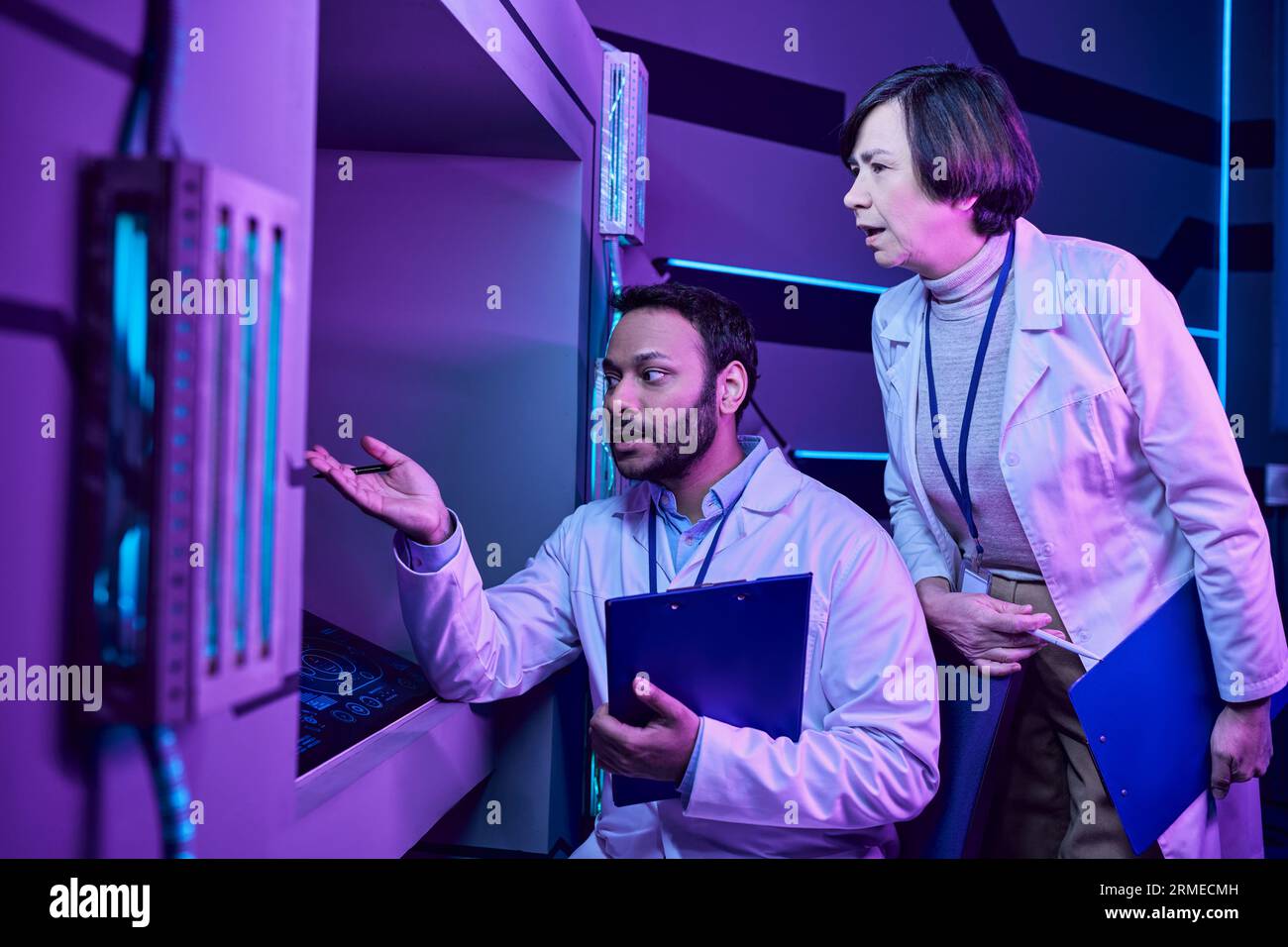 Gli scienziati indù maschi e adulti femminili si impegnano con il computer nel Neon-Lit Science Center Foto Stock
