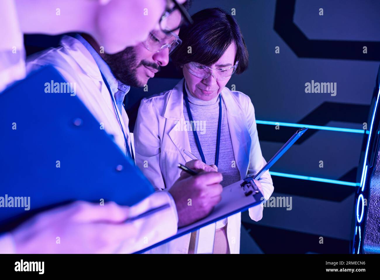 Documentazione futuristica: Tre scienziati record Parameters nel Neon-Lit Science Center Foto Stock