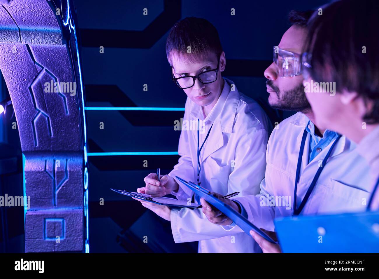 Scambio futuristico: Tre scienziati e uno stagista osservano i colleghi del Neon-Lit Science Center Foto Stock