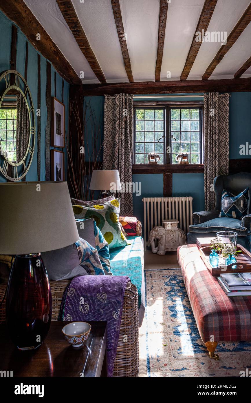 Poltrona e divano nella sala televisione "Stone Blue" con finestre in vetro piombato. Casa colonica Tudor a Surrey, Regno Unito Foto Stock