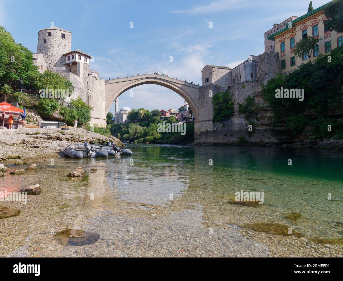 Stari Most (Ponte Vecchio) con barche sulla spiaggia lungo il fiume Neretva con barche. Città di Mostar, Bosnia ed Erzegovina, 26 agosto 2023. Foto Stock