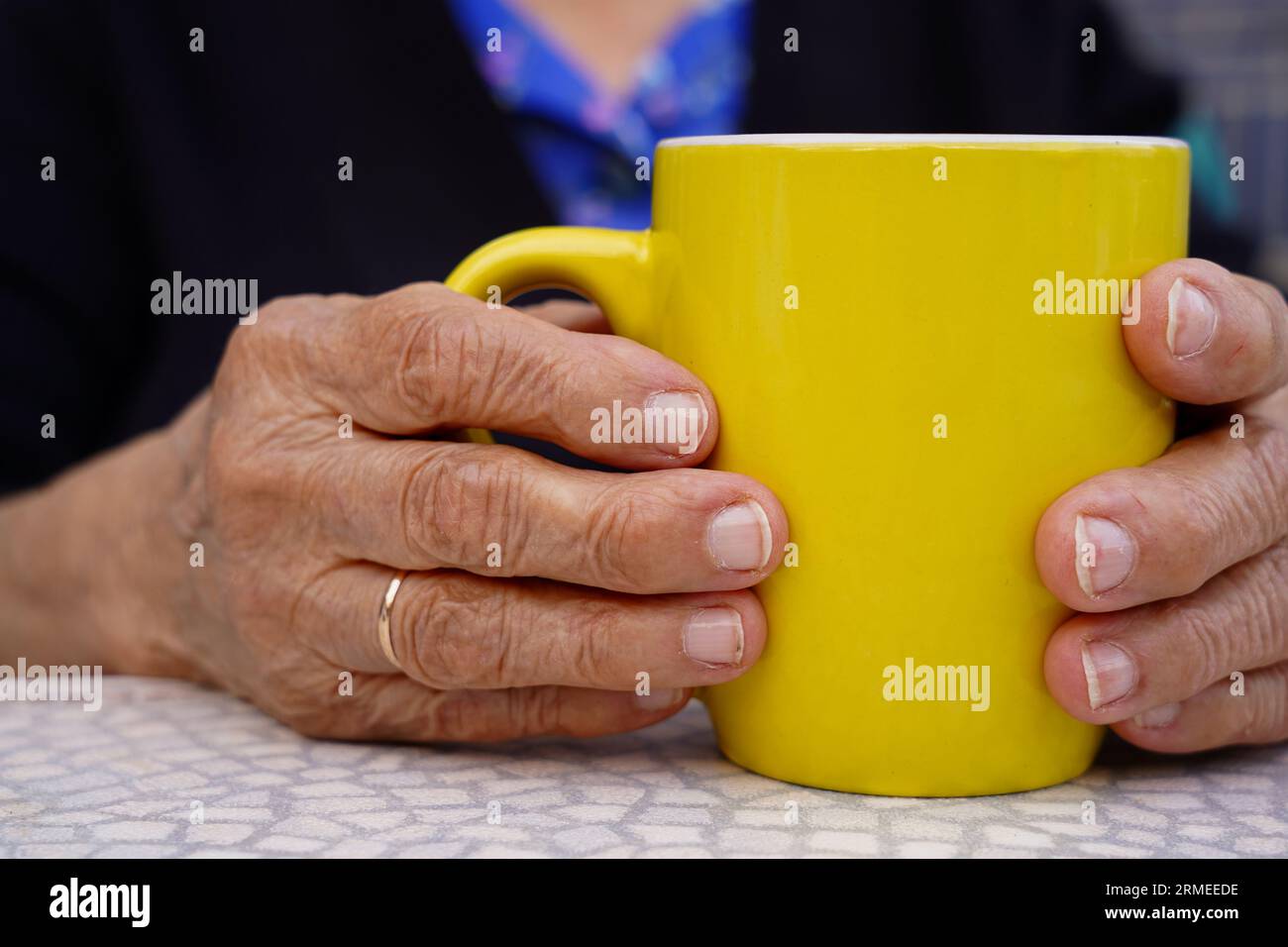 donna matura irriconoscibile che beve una tazza gialla. Stile di vita anziano con rughe Foto Stock
