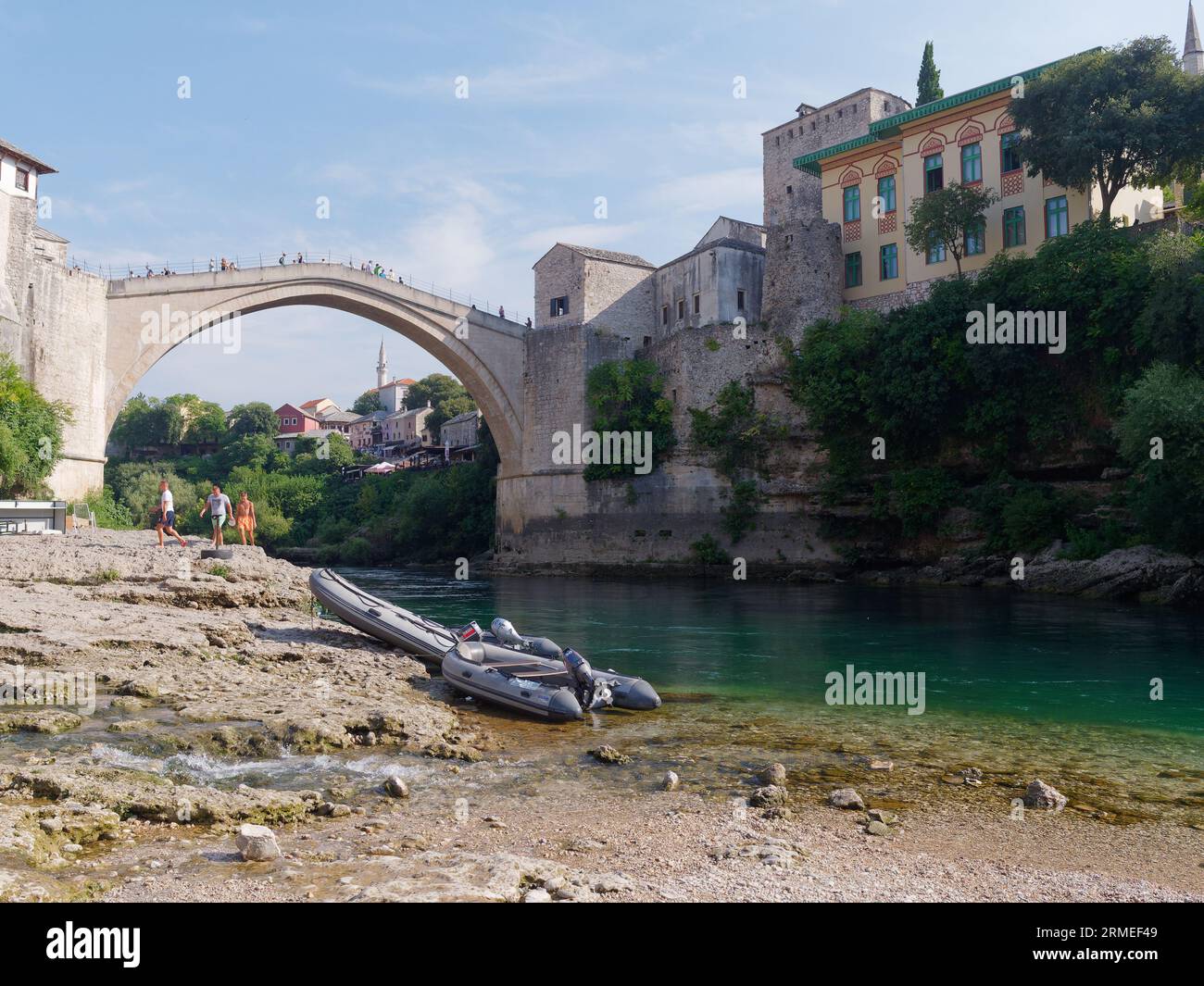 Stari Most (Ponte Vecchio) con barche sulla spiaggia lungo il fiume Neretva con barche. Città di Mostar, Bosnia ed Erzegovina, 26 agosto 2023. Foto Stock
