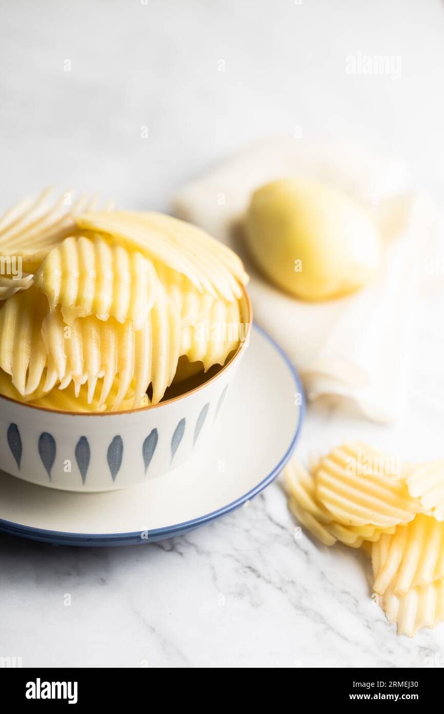 Fette e patate intere posizionate su una tavola di marmo bianco. Foto Stock