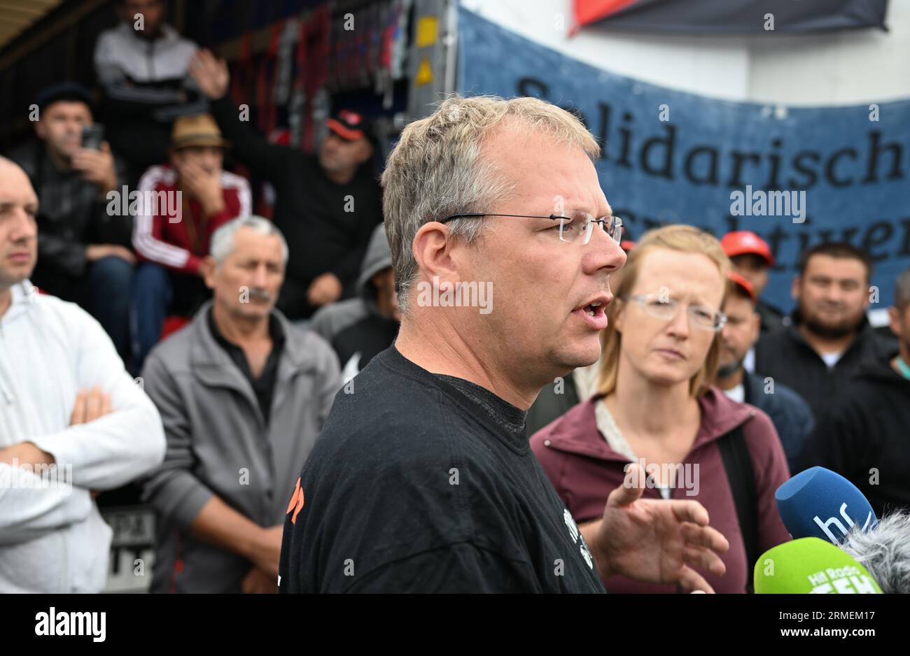 28 agosto 2023, Assia, Gräfenhausen: Il sindacalista olandese Edwin Atema, nominato dai camionisti dell'Europa orientale per guidare i negoziati, parla durante una conferenza stampa alla presenza degli uomini. I conducenti di un'azienda di trasporti polacca proveniente dall'Uzbekistan, dalla Georgia e da altri paesi dell'Europa orientale e dell'Asia centrale scioperano nell'area di servizio dell'Assia meridionale da quasi sei settimane. Gli uomini chiedono salari eccezionali. (Al dpa "parlamentare europeo per i conducenti in sciopero: Sono necessari più controlli") foto: Arne Dedert/dpa Foto Stock