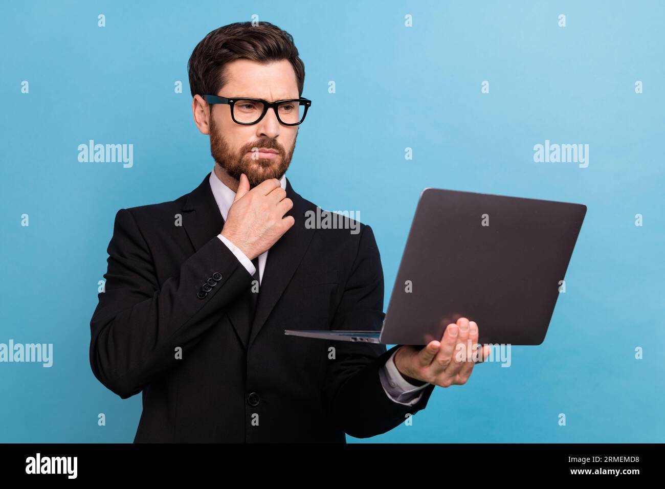 Foto di un manager intelligente e premuroso vestito da occhiali da vista nero che legge messaggi dispositivo moderno con sfondo blu isolato Foto Stock