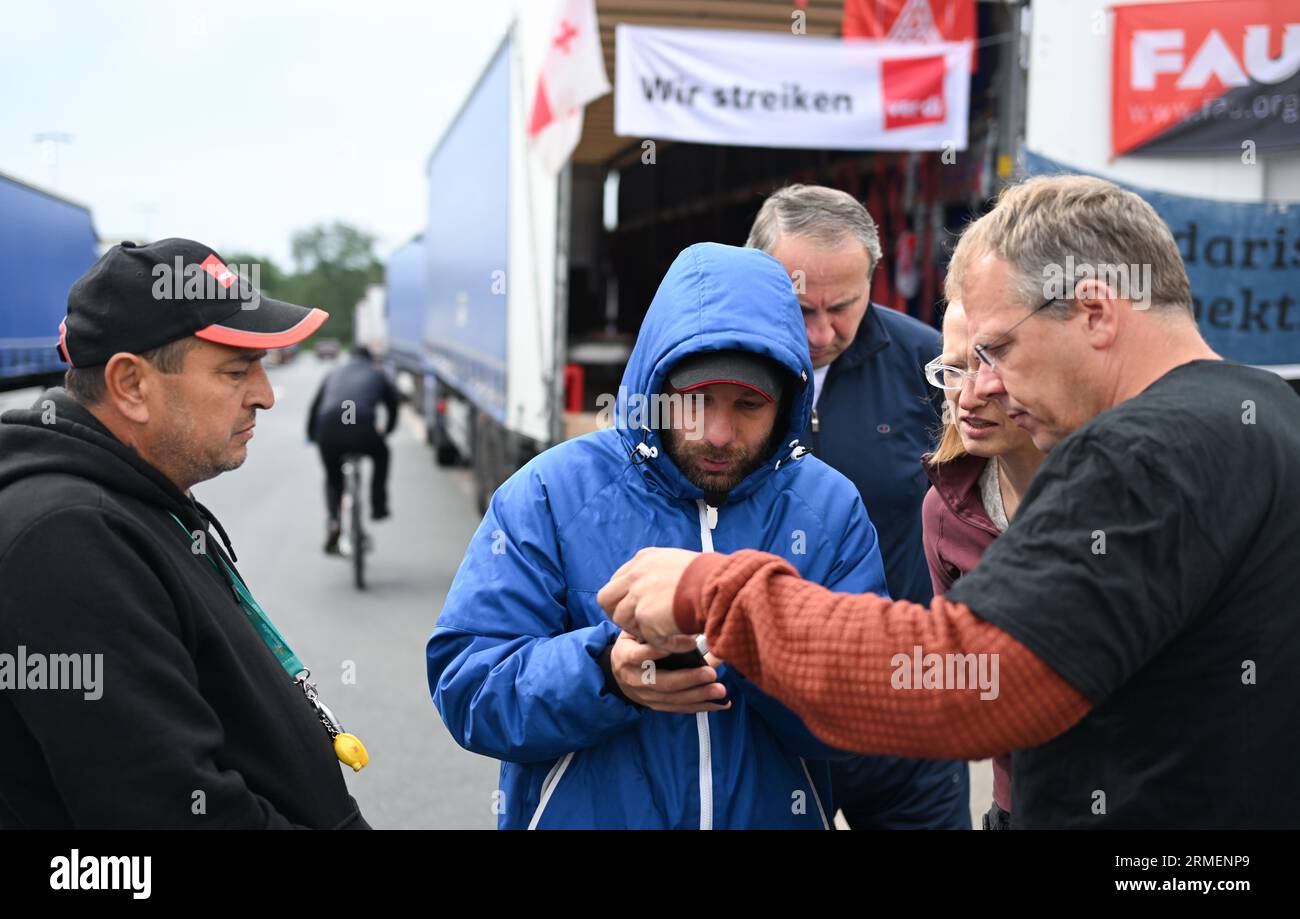 28 agosto 2023, Assia, Gräfenhausen: Il sindacalista olandese Edwin Atema (r), che è stato nominato dai camionisti dell'Europa orientale per condurre le trattative, parla con i conducenti. I conducenti di un'azienda di trasporti polacca proveniente dall'Uzbekistan, dalla Georgia e da altri paesi dell'Europa orientale e dell'Asia centrale scioperano nell'area di servizio dell'Assia meridionale da quasi sei settimane. Gli uomini chiedono salari eccezionali. (Al dpa "parlamentare europeo per i conducenti in sciopero: Sono necessari più controlli") foto: Arne Dedert/dpa Foto Stock