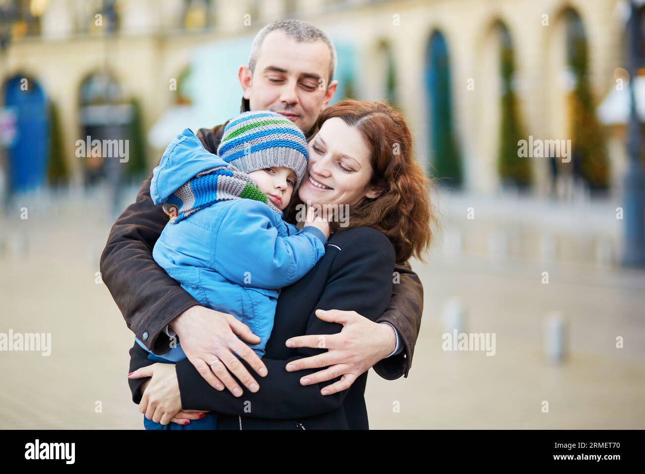 Felice famiglia di tre persone che camminano insieme in una strada di Parigi Foto Stock