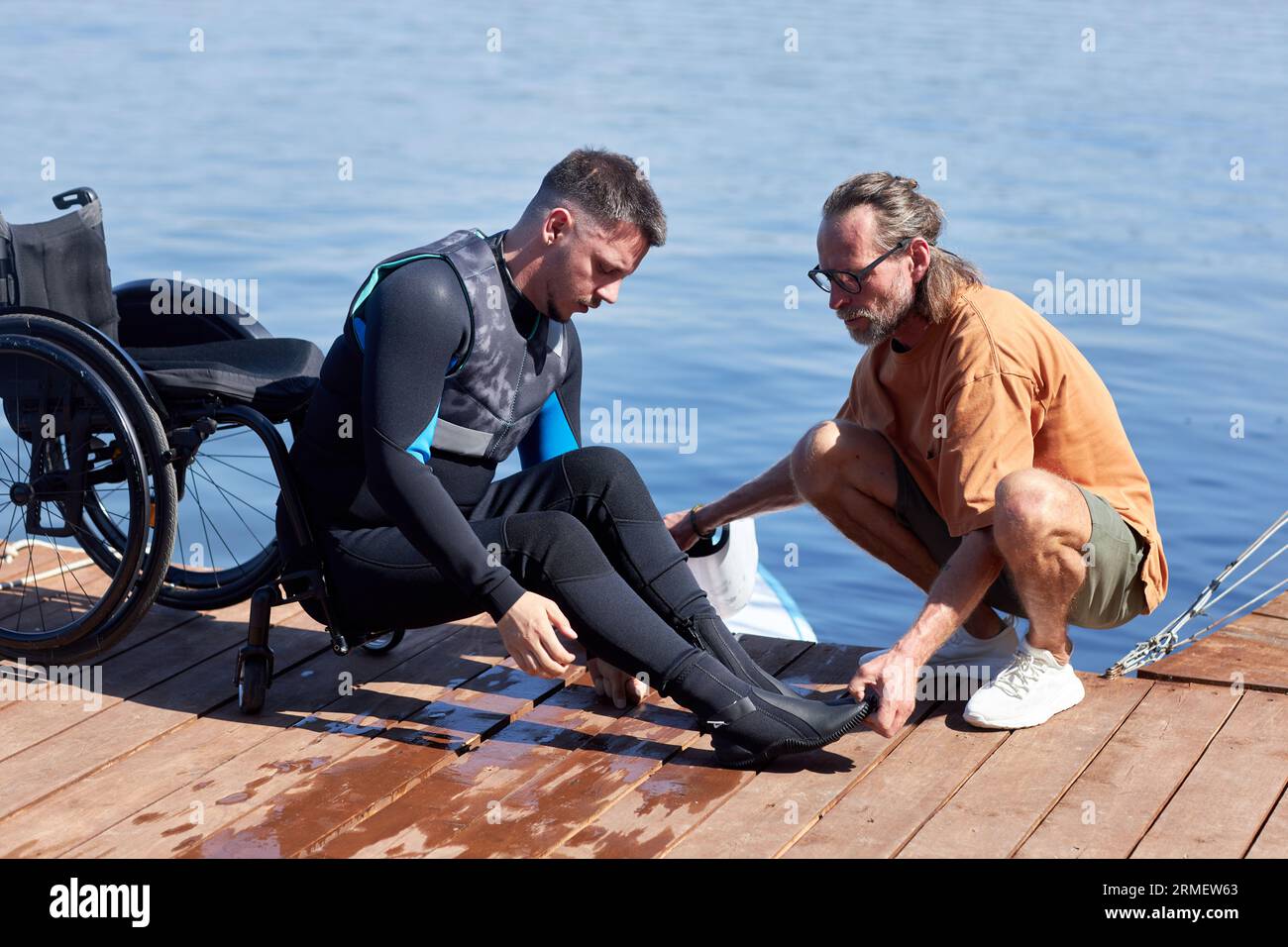 Ritratto laterale di un uomo con disabilità che si prepara ad andare a wakeboard con attrezzature adattive Foto Stock