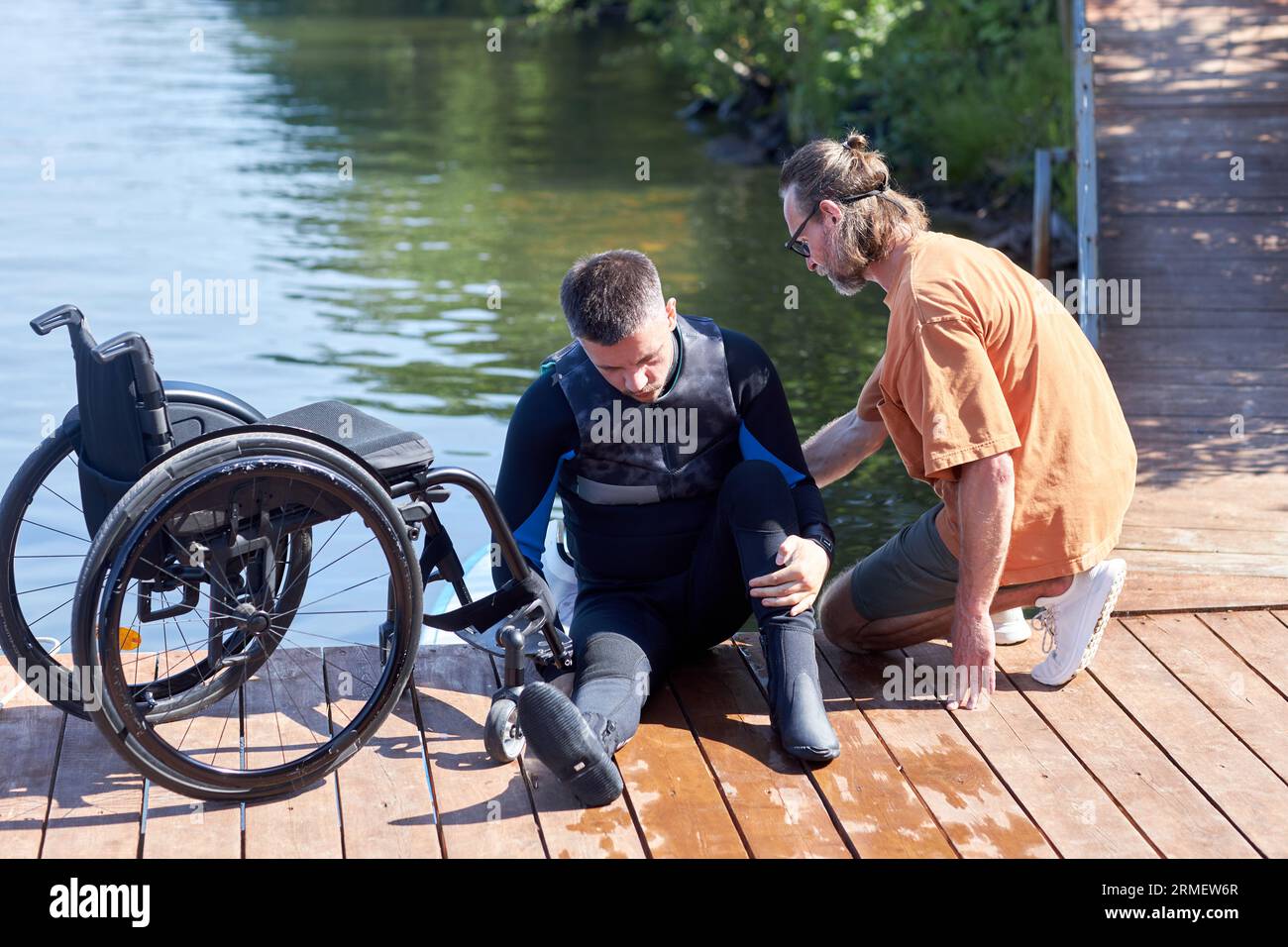 Ritratto completo dell'uomo con disabilità che si prepara a praticare sport acquatici con attrezzature adattive Foto Stock